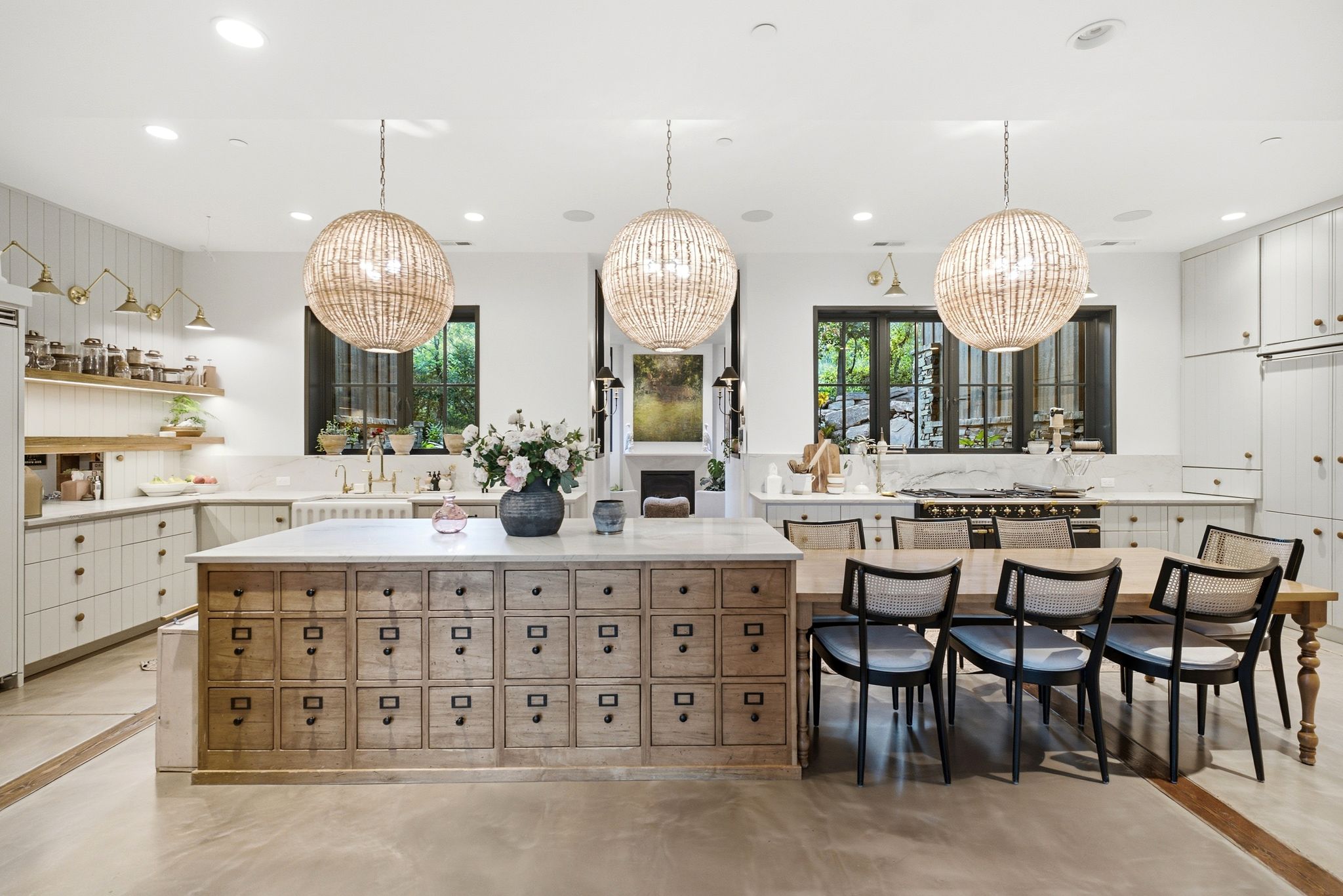 Kitchen featuring an oversized island with extensive drawer storage, integrated dining table, and three large pendant lights