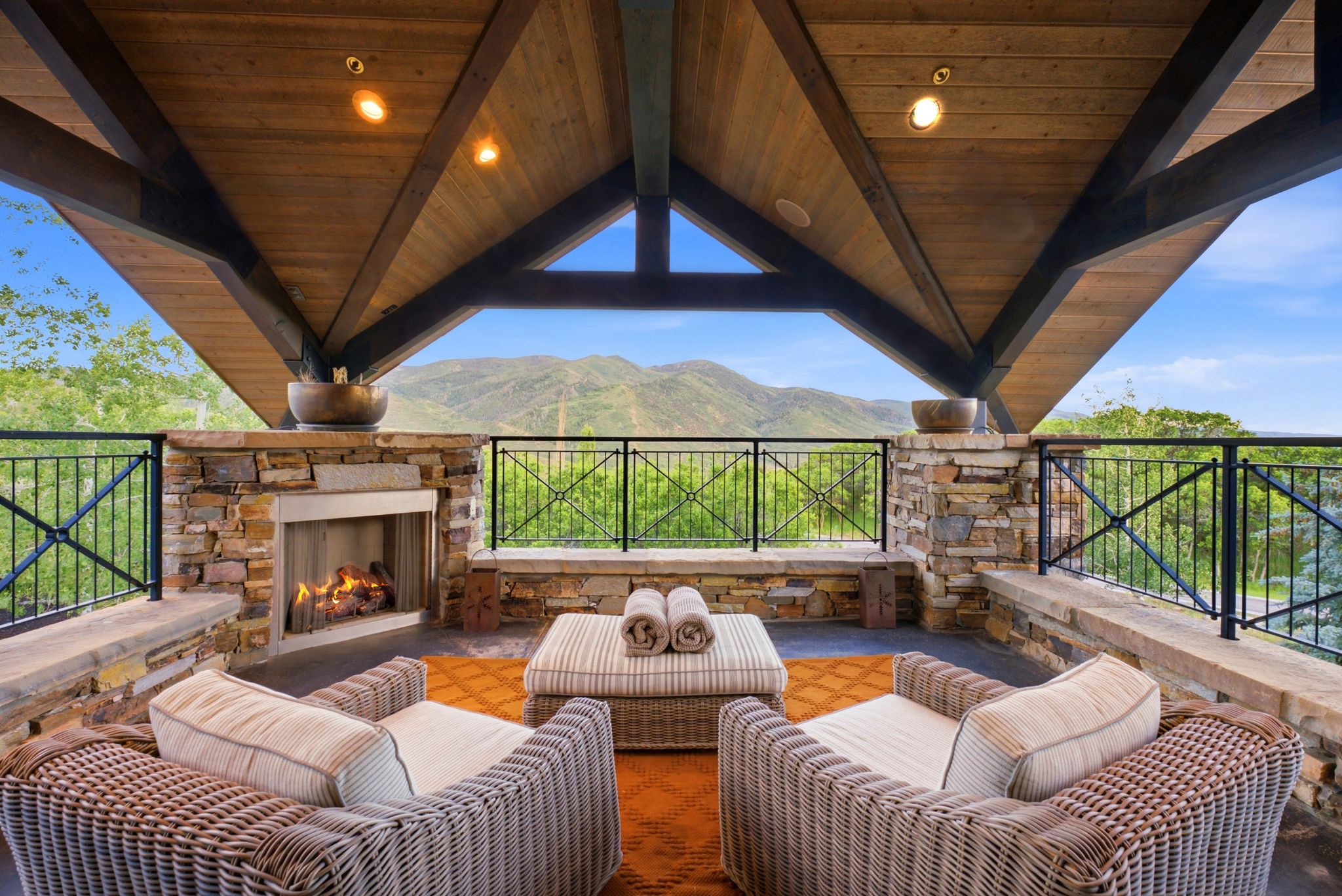Covered outdoor patio featuring a stone-clad fireplace and wood-plank vaulted ceiling
