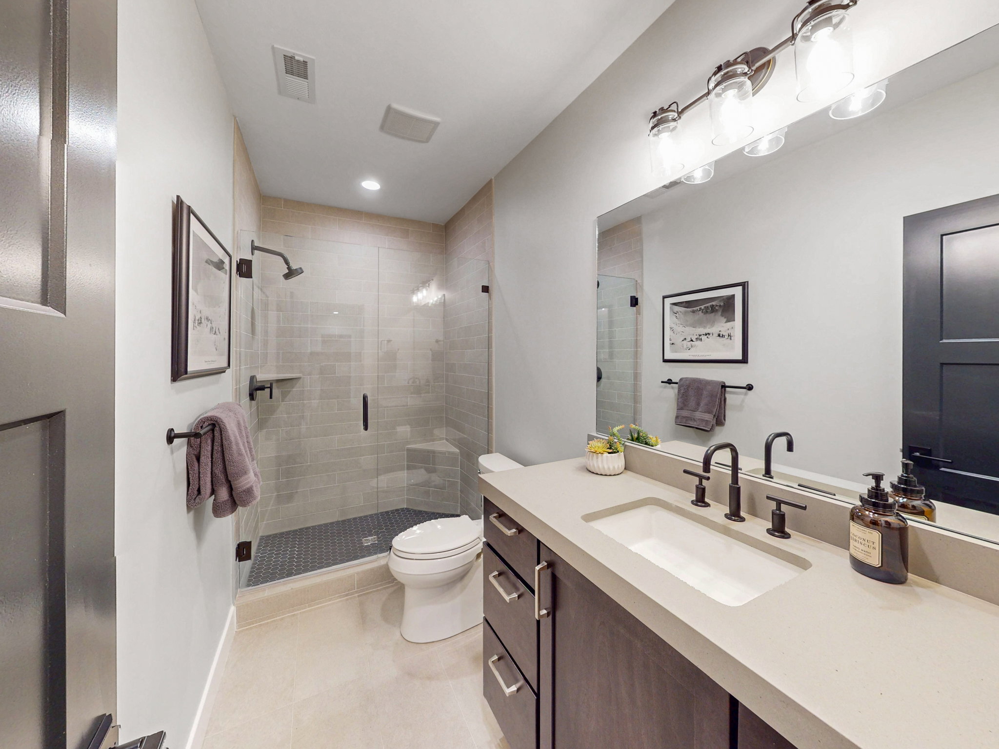 Second lower level bathroom is a contemporary featuring a dark wood-finish vanity with an integrated sink and light-toned countertop