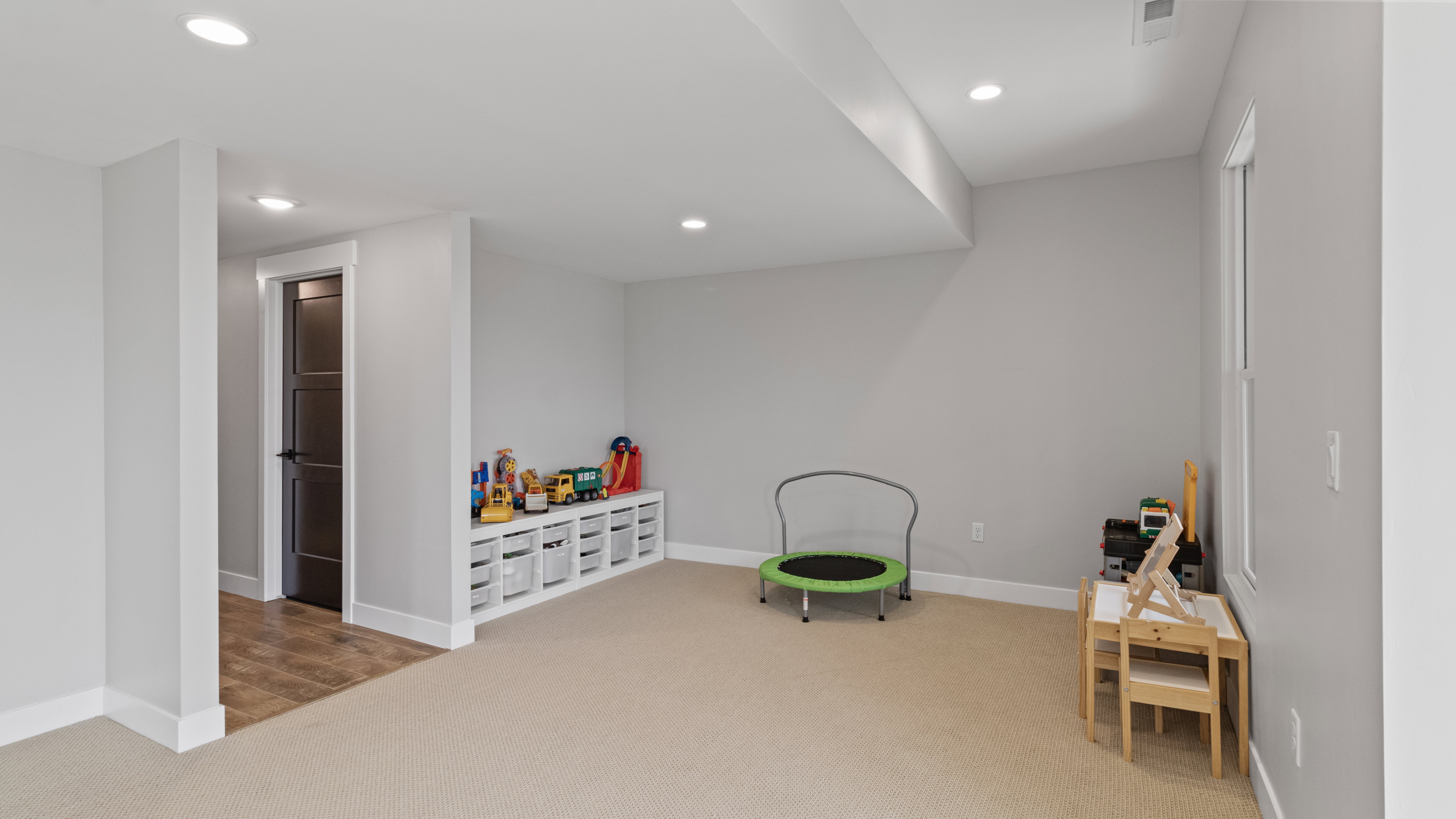 Spacious room featuring neutral carpeting, light gray walls, recessed lighting, and white trim