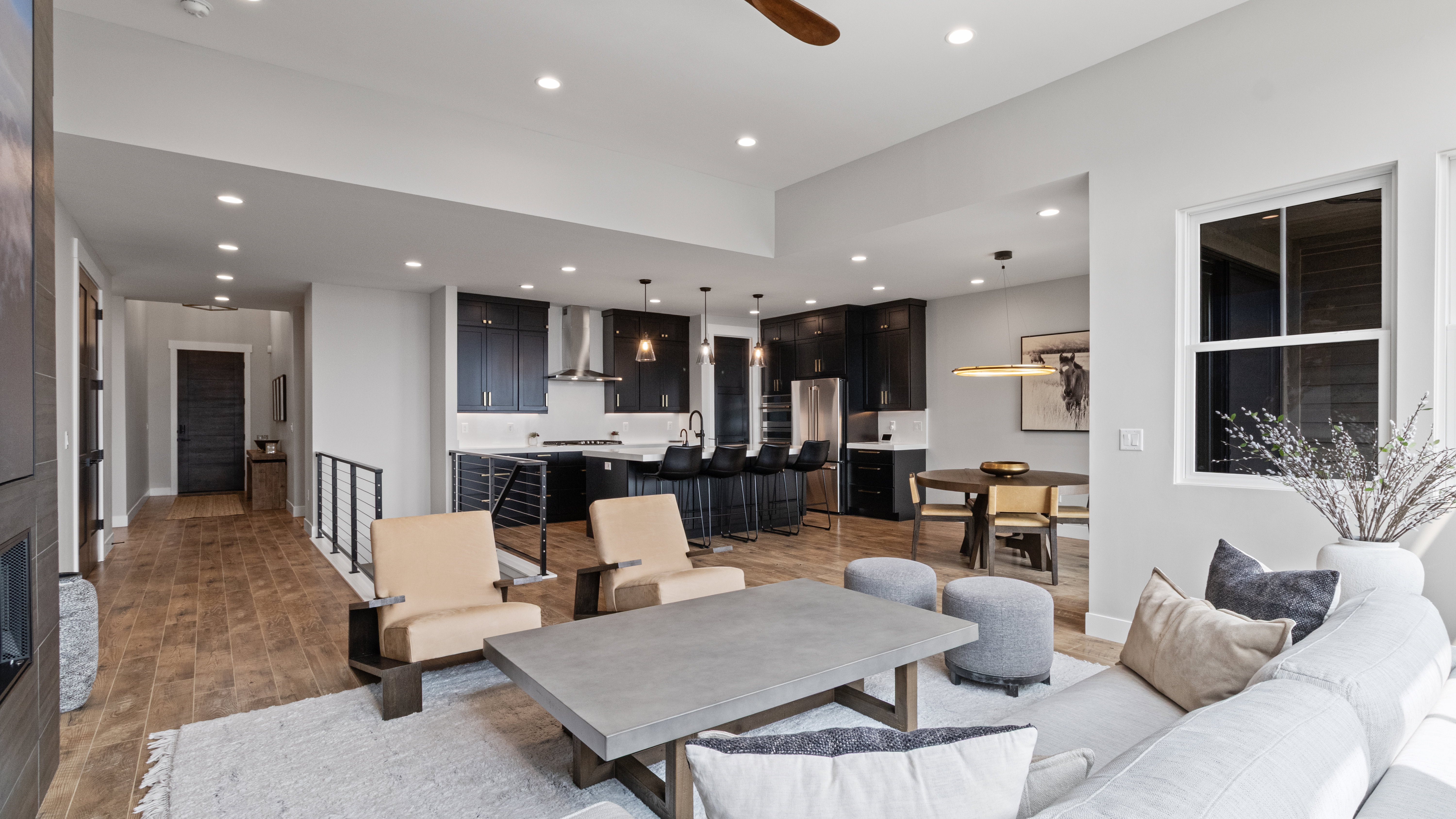 Open-concept living area with wood-finish flooring, recessed lighting, and a modern kitchen featuring dark cabinetry and light countertops