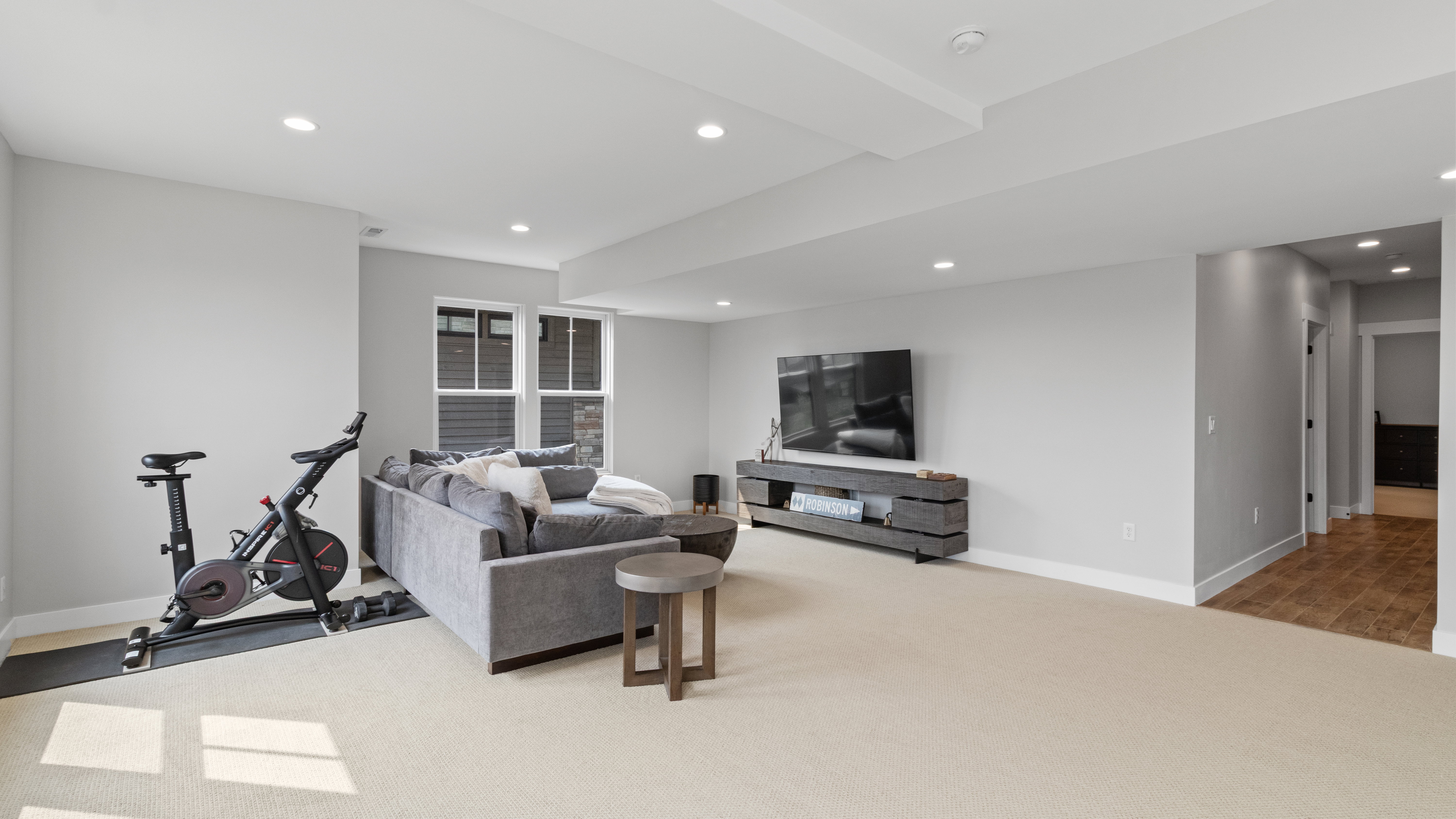 Spacious recreation room featuring recessed lighting, light-toned carpeting, and a window with blinds
