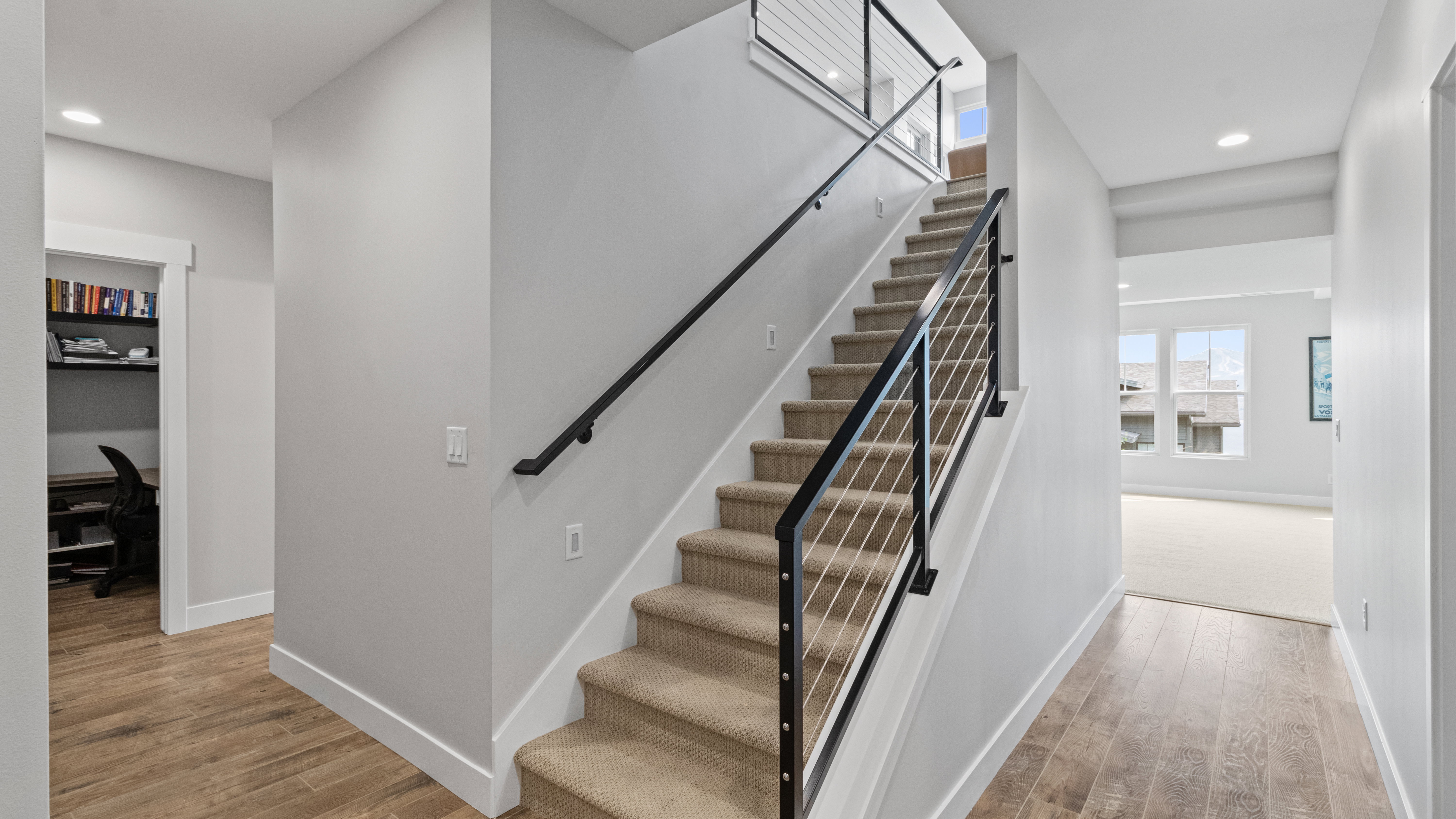 Modern staircase with cable railing, carpeted treads, and wood-finish flooring