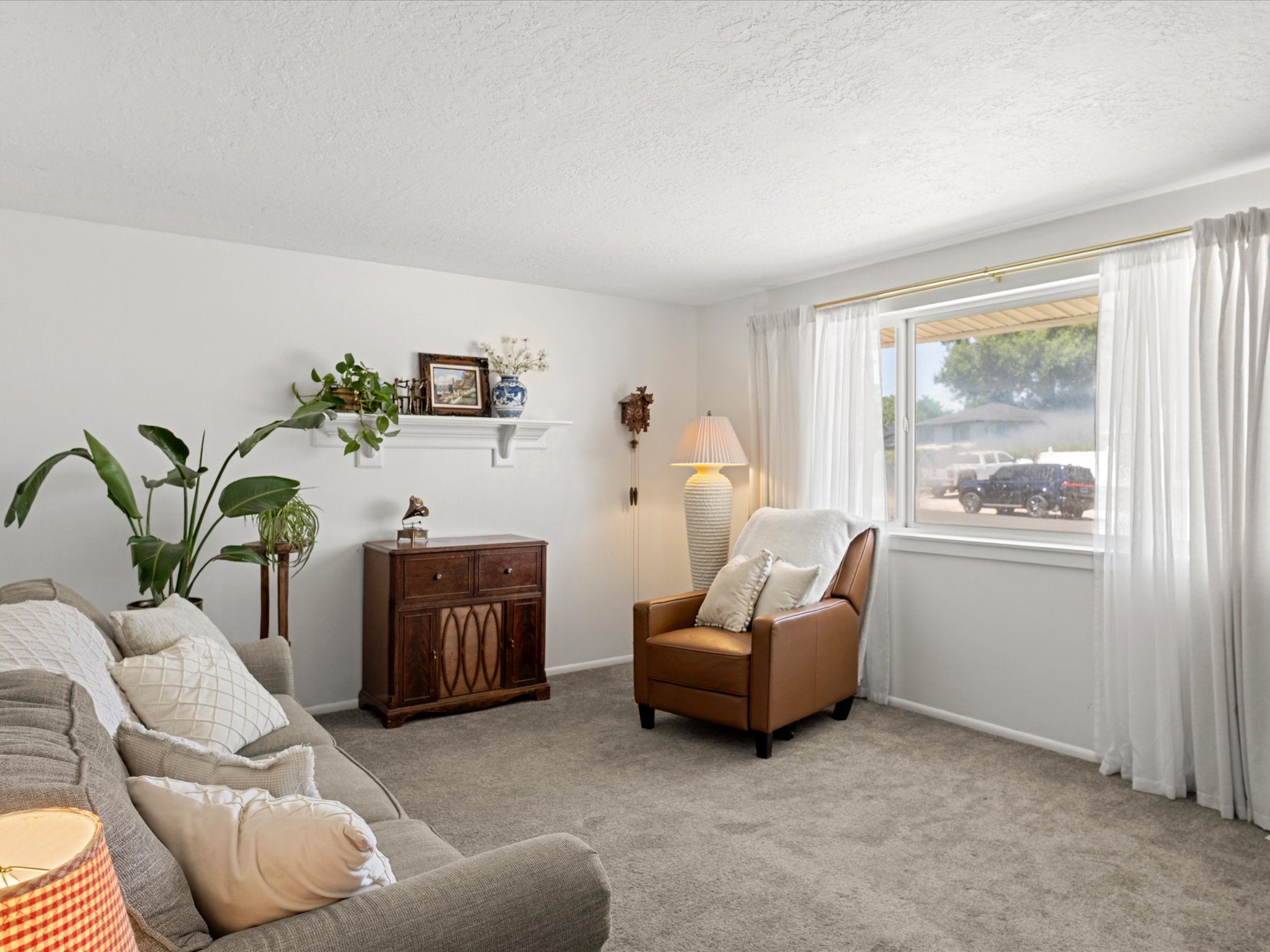 Bright living space featuring a window with natural light, light-toned walls, and carpet flooring