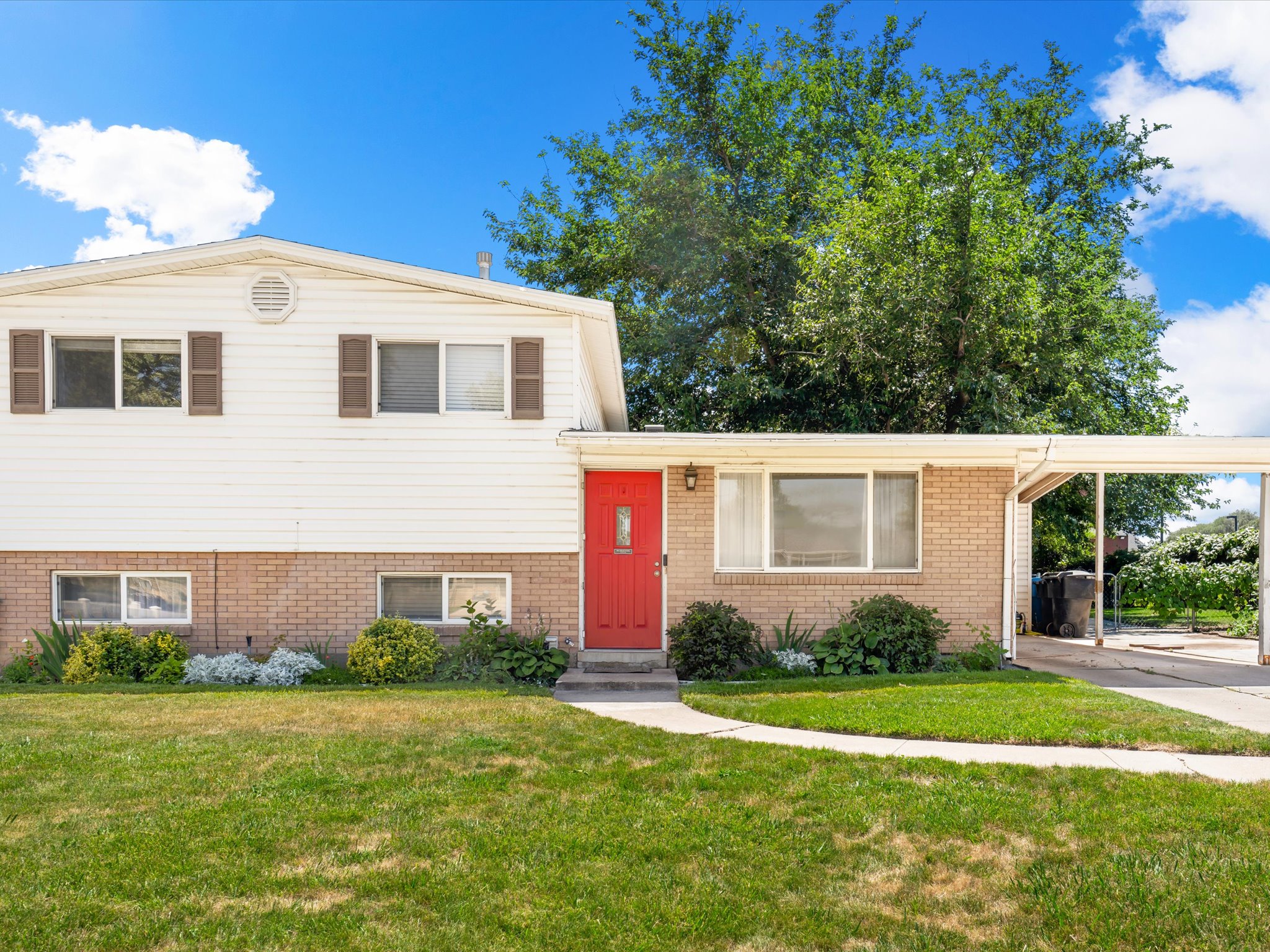 Split-level exterior featuring white siding and brick accents