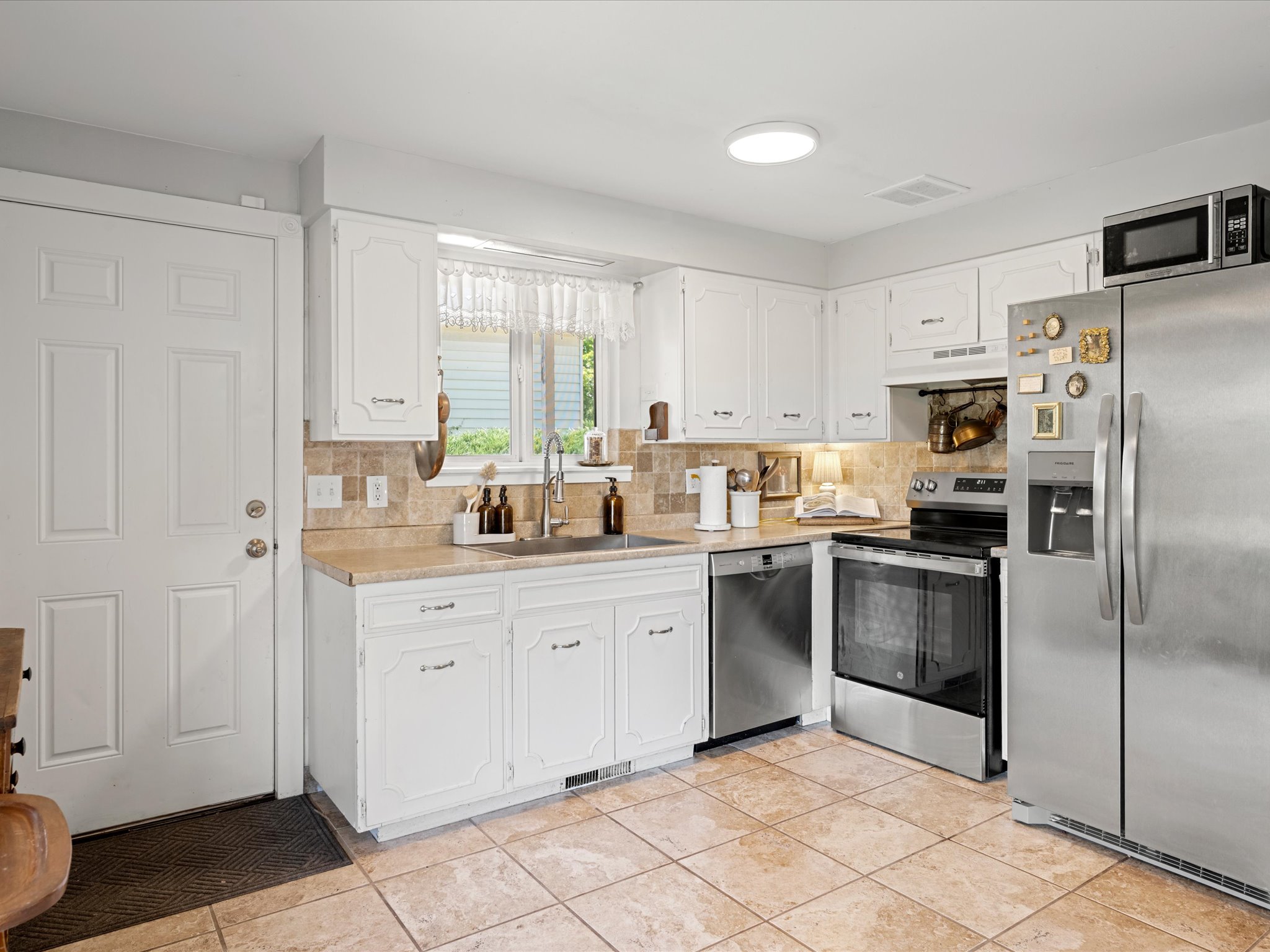 Bright kitchen featuring white cabinetry, a neutral tiled backsplash