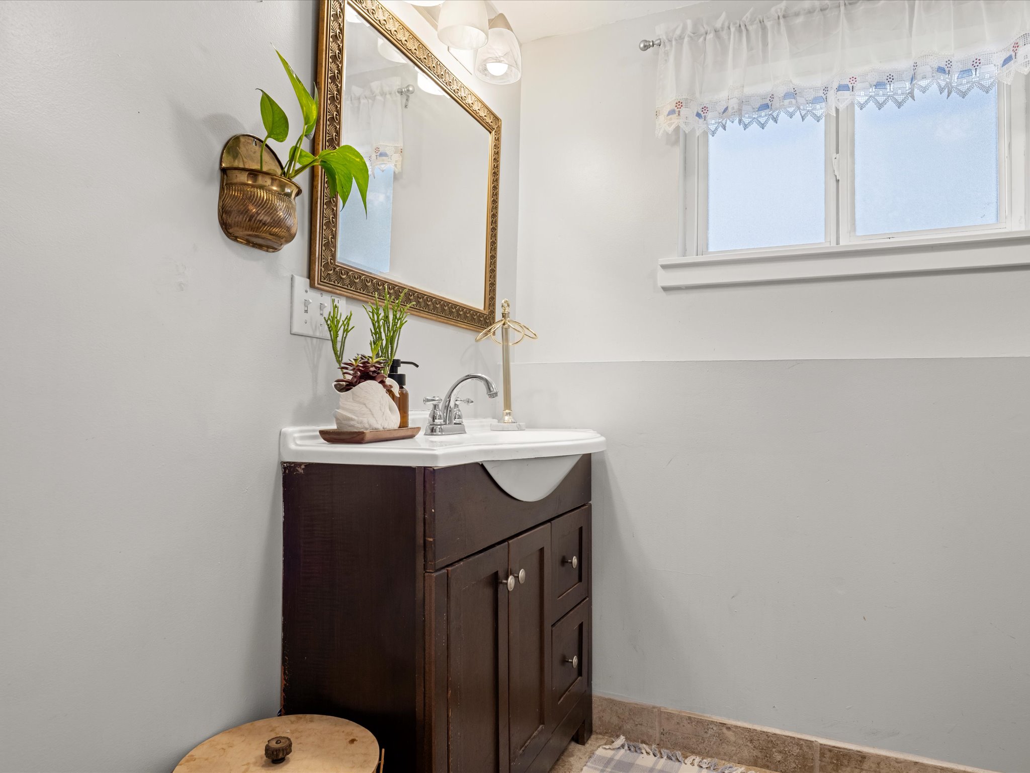 Vanity with dark wood cabinetry, white integrated sink basin, and chrome faucet