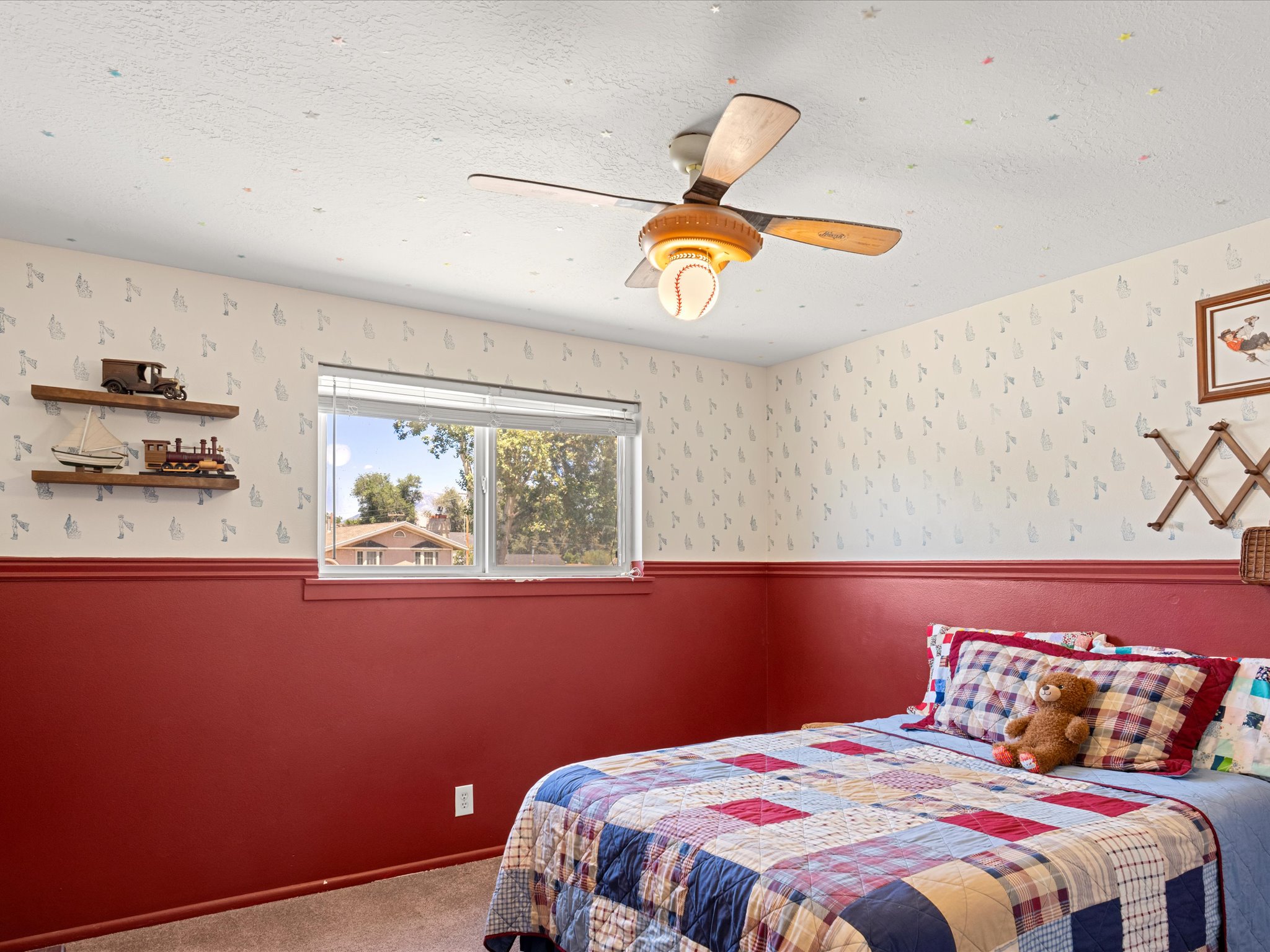 Room featuring a ceiling fan with light fixture, window with blinds, and wall-mounted shelving
