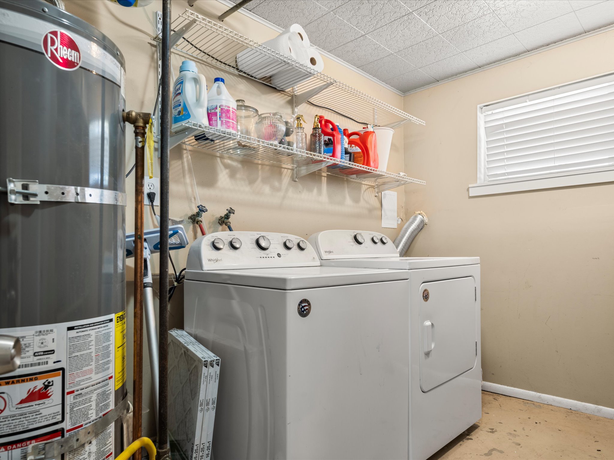 Laundry room featuring white wall-mounted shelving and a single window with white blinds