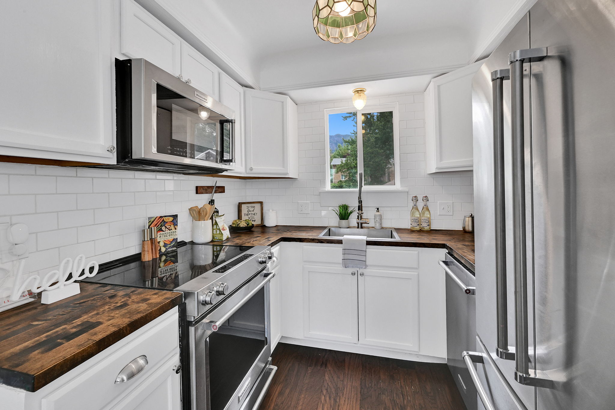 Modern kitchen featuring white shaker cabinetry, stainless steel appliances, wood-finish countertops, and white subway tile backsplash