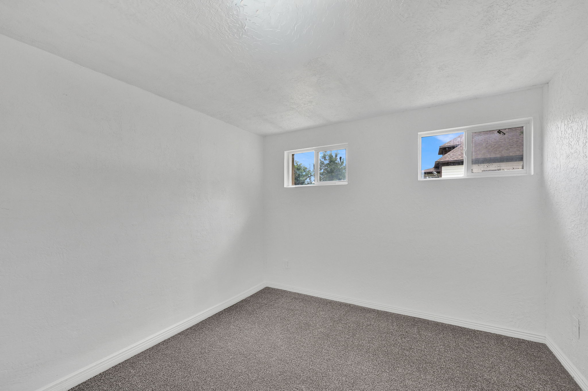 Room featuring two windows, neutral wall tones, and gray carpet flooring