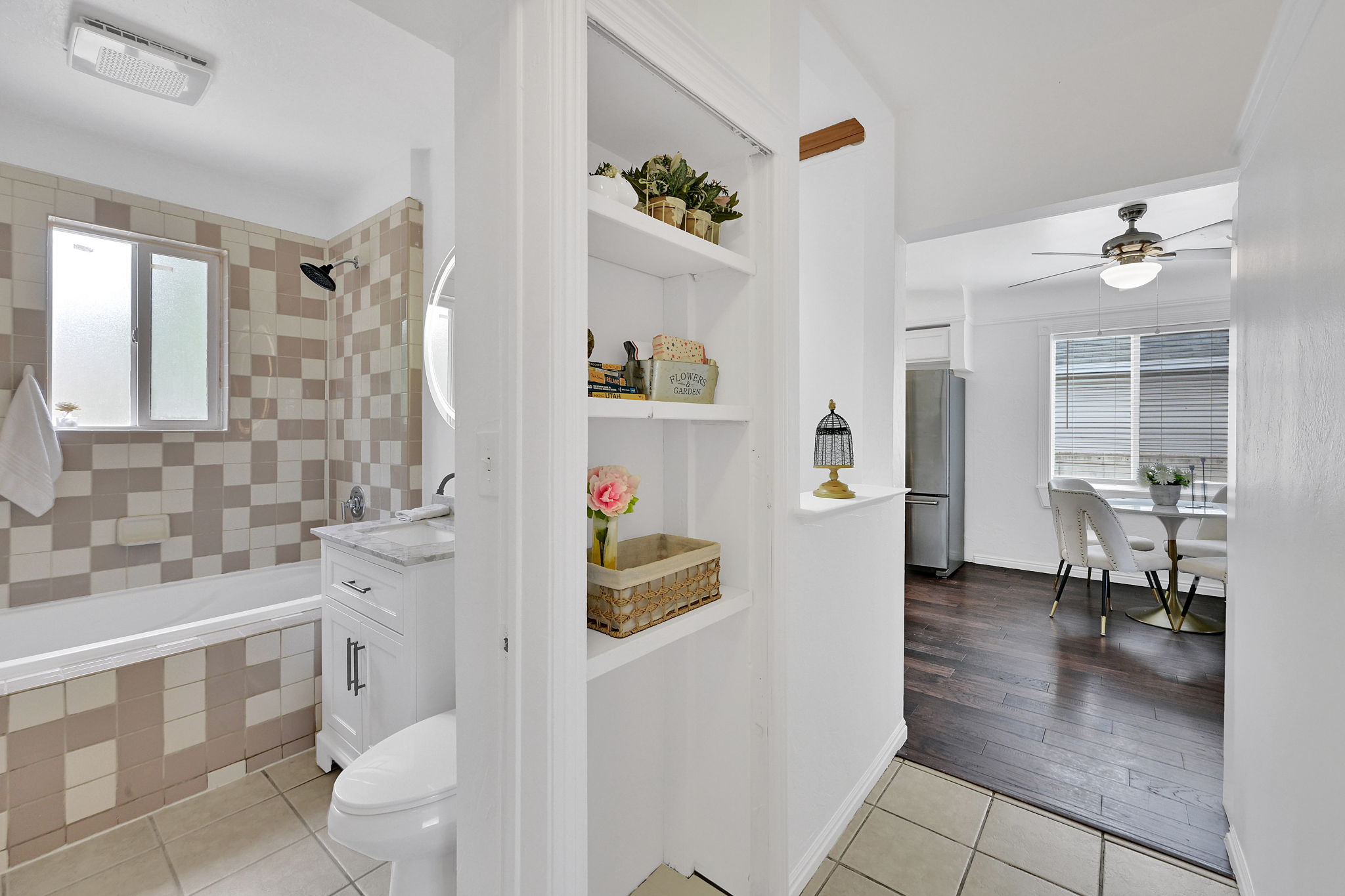 Bathroom featuring patterned wall tiling, a white bathtub, and a vanity with a white countertop and dark fixtures