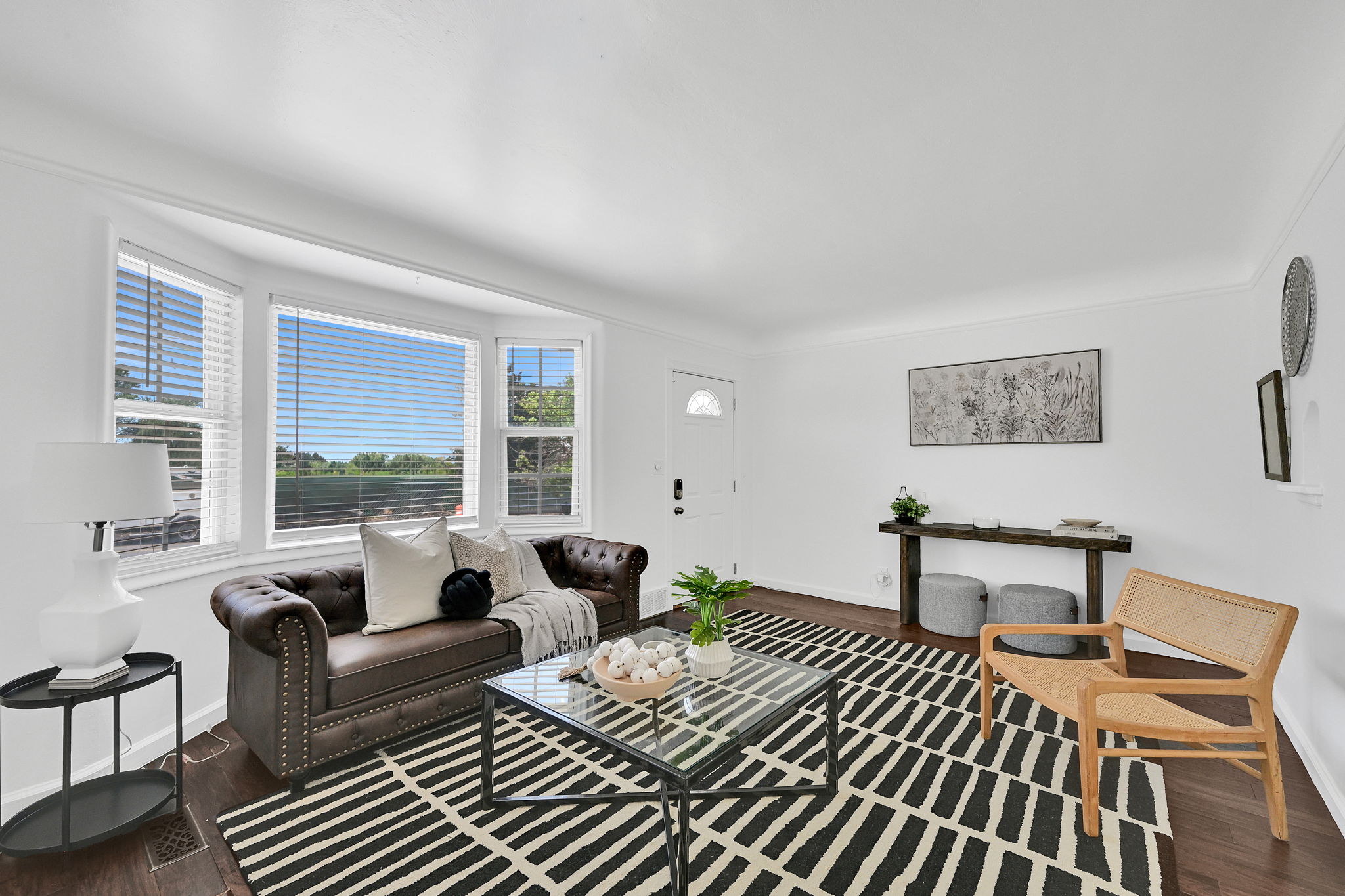Living space featuring a bay window, wood-finish flooring, white walls, and a front entry door with a decorative glass insert