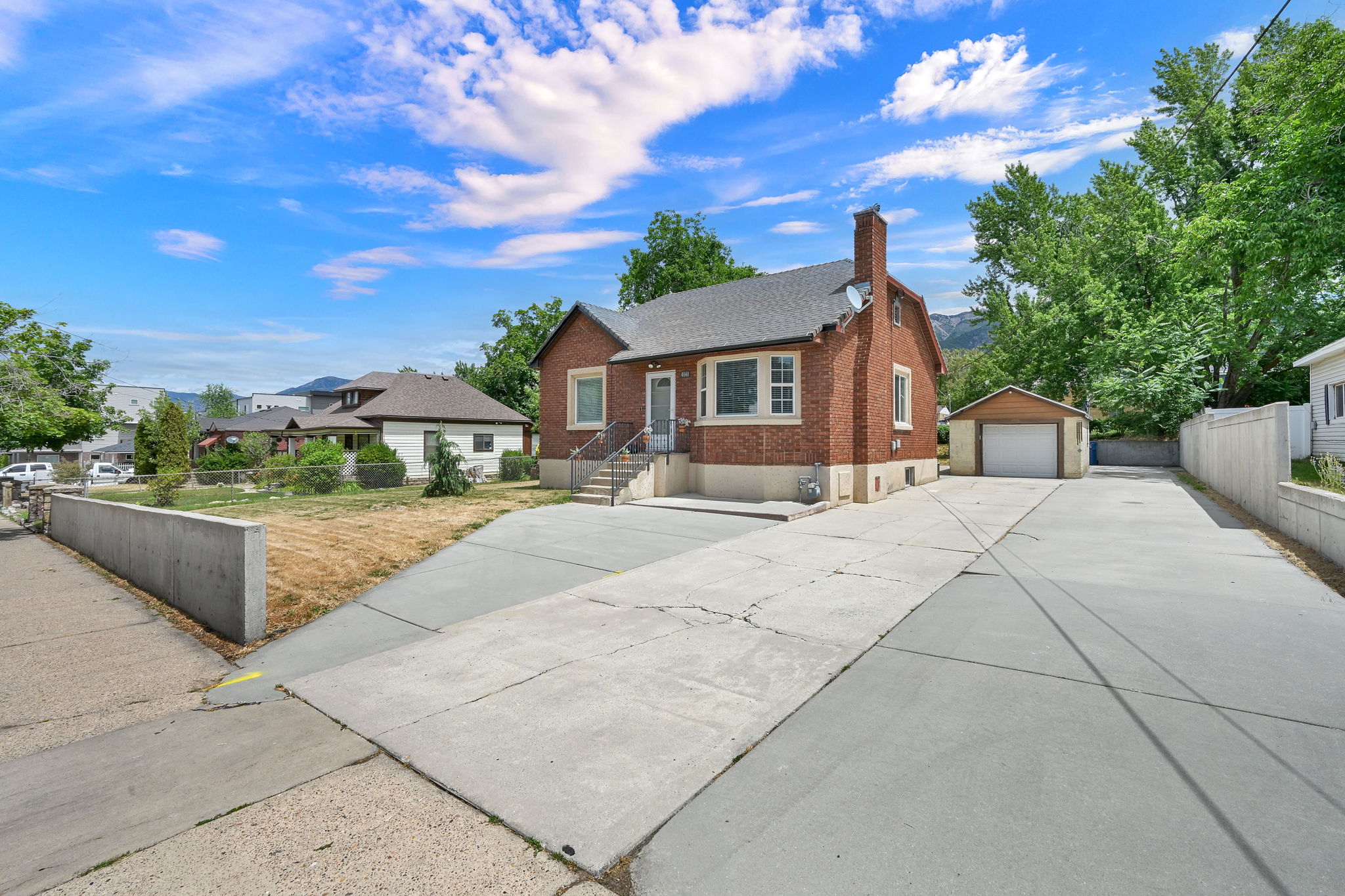 Brick exterior residence featuring a detached garage and an extended concrete driveway