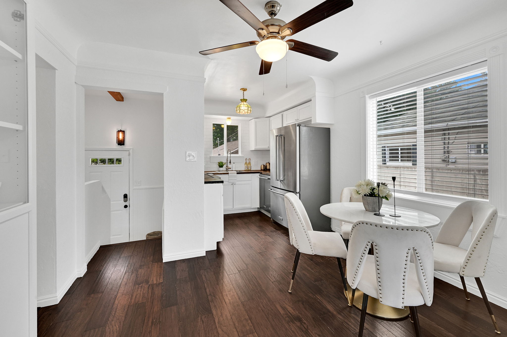 Wood-finish flooring throughout, featuring a bright dining area with a large window and a ceiling fan