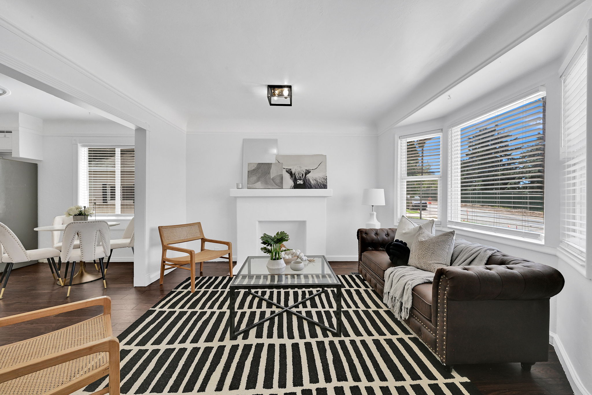 Spacious living area featuring dark wood-finish flooring, a decorative fireplace, and a large bay window