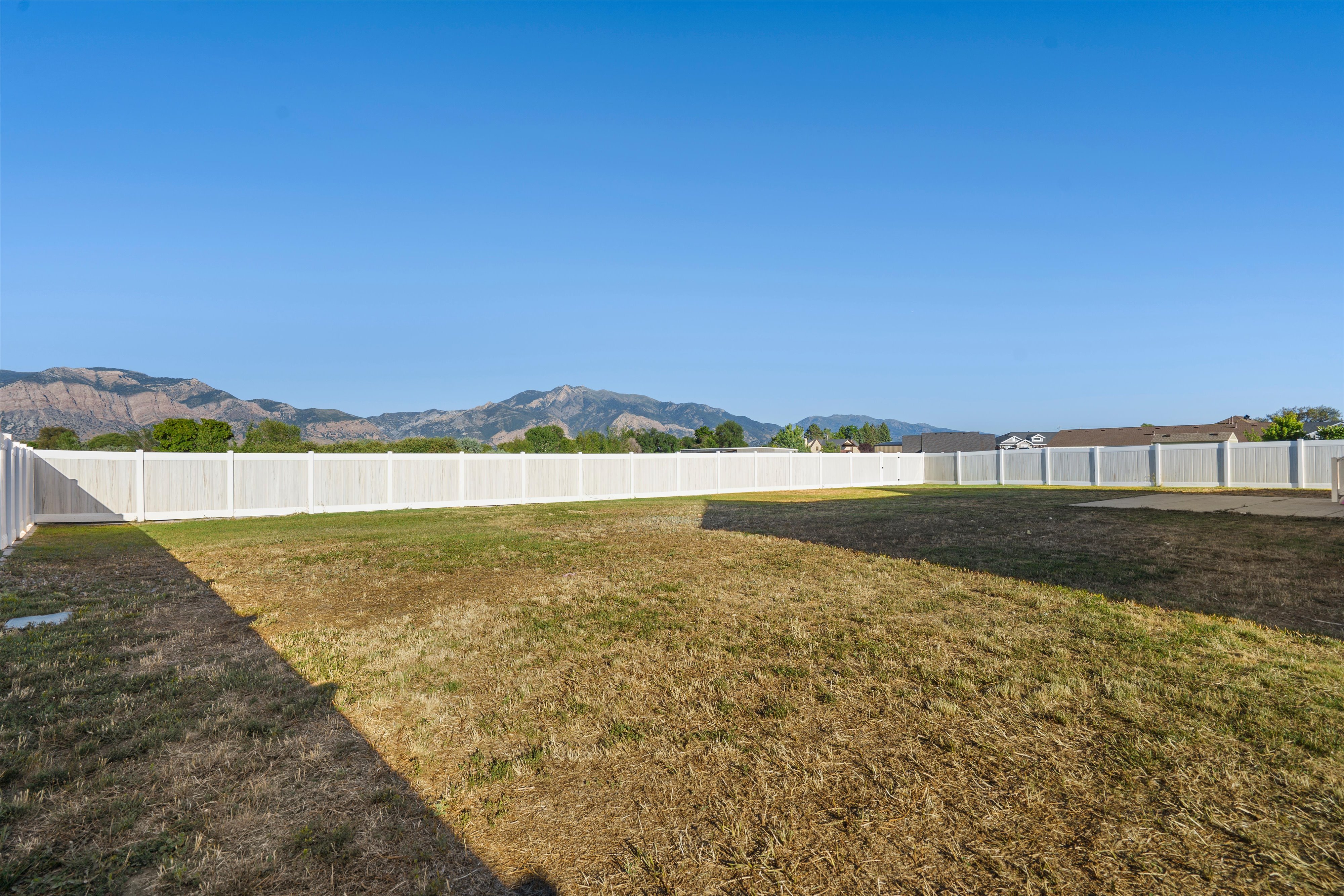 Expansive backyard featuring a white vinyl privacy fence and a concrete pad