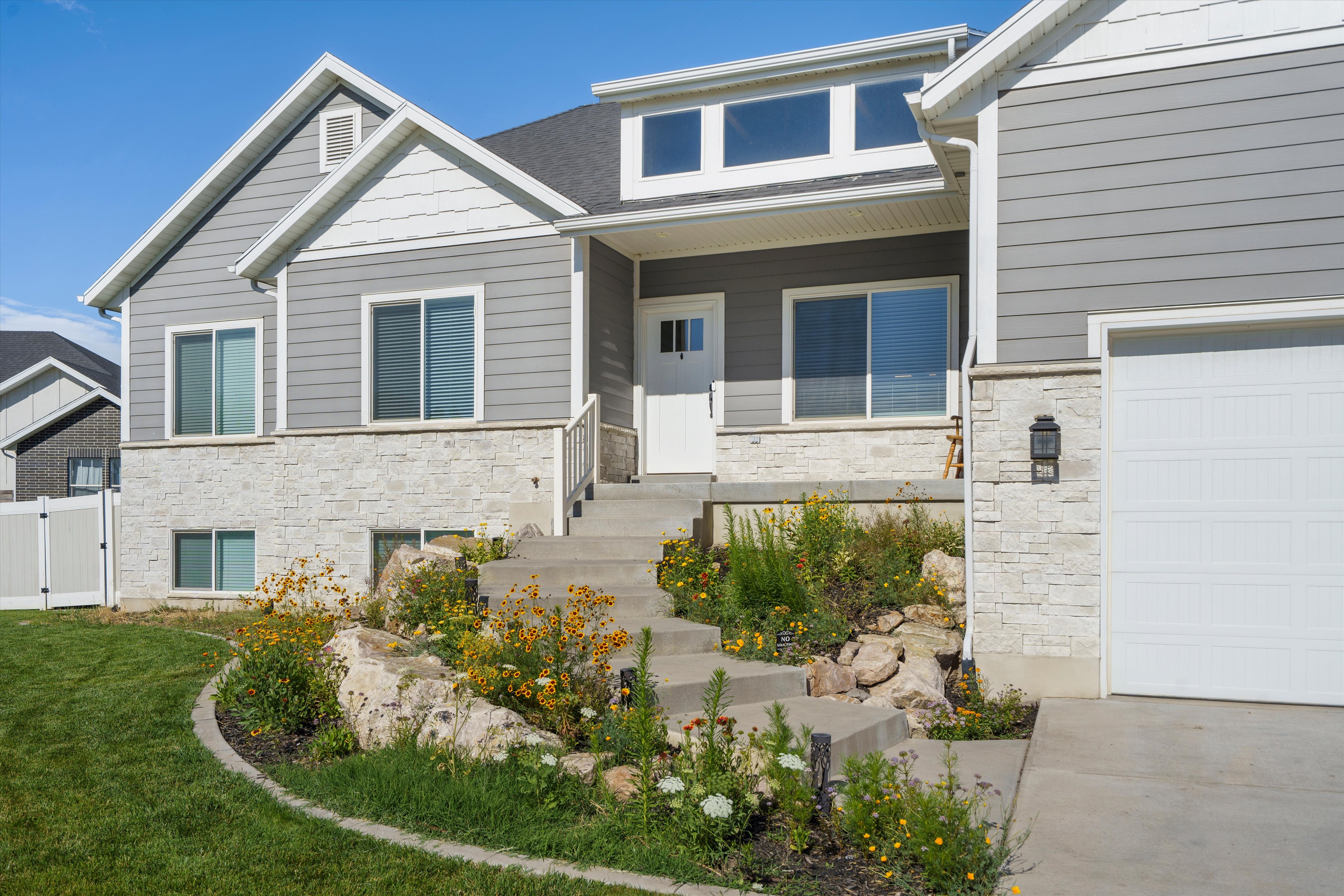 Contemporary facade featuring gray horizontal siding and white stone veneer accents