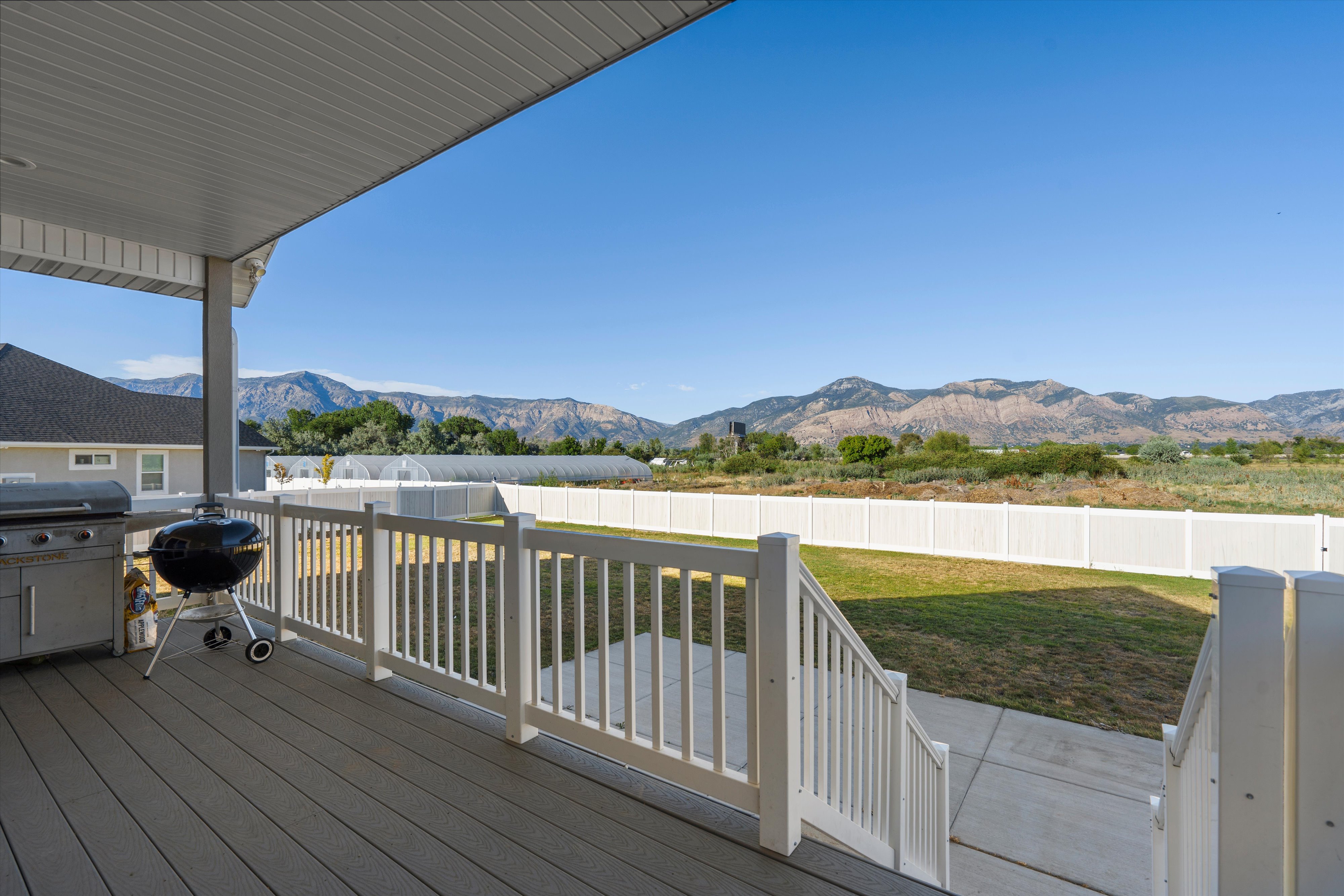 Covered deck with composite decking, white railing, and mountain backdrop