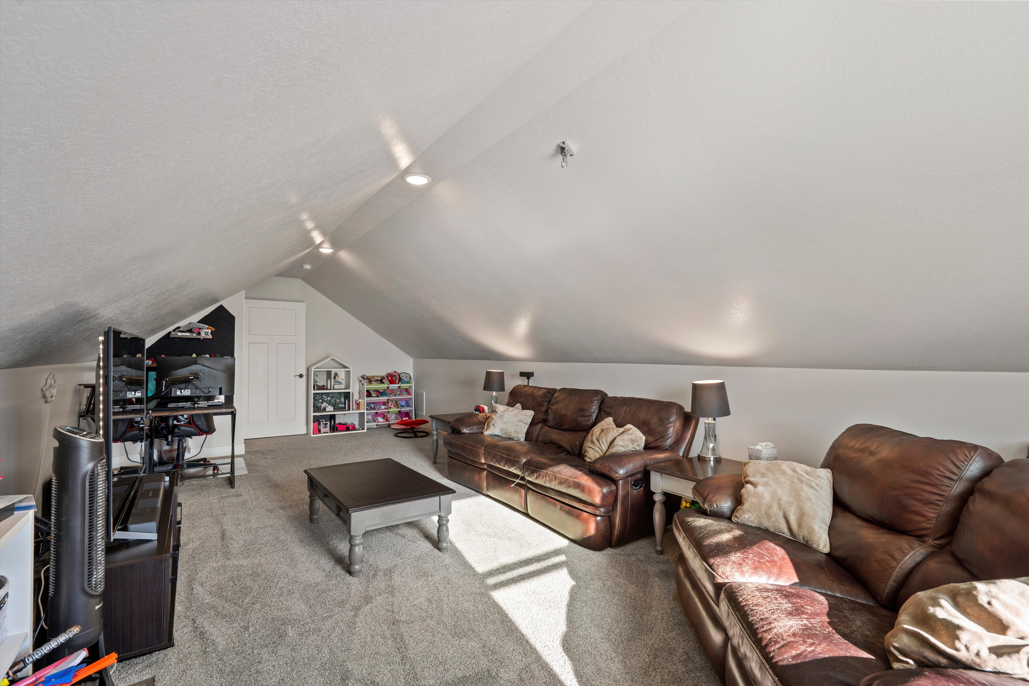 Carpeted loft area featuring a sloped ceiling with recessed lighting, a white paneled door, and a built-in shelf