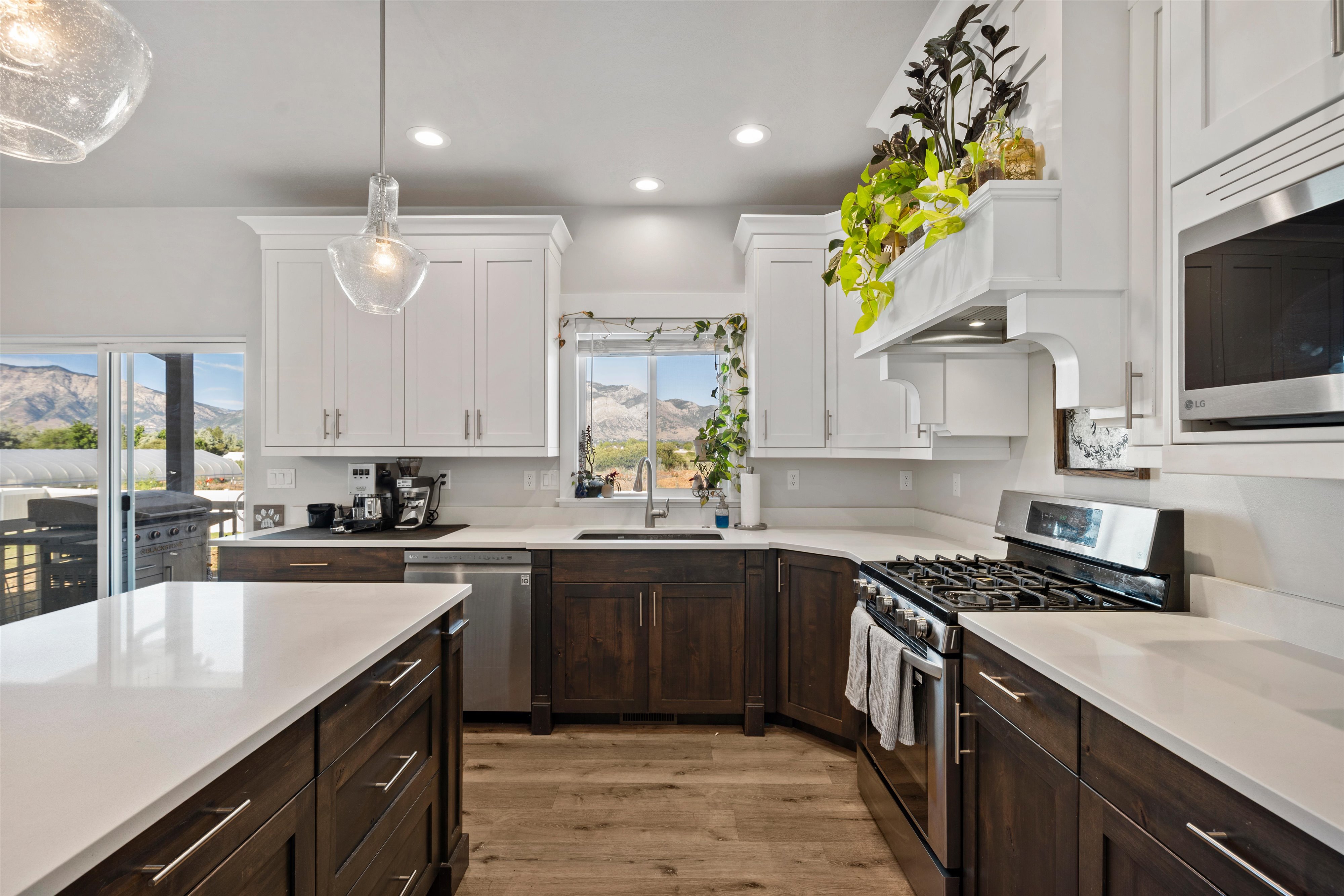 Gourmet kitchen featuring a central island with white countertop, dark wood-finish cabinetry, stainless steel appliances, and wood-finish flooring