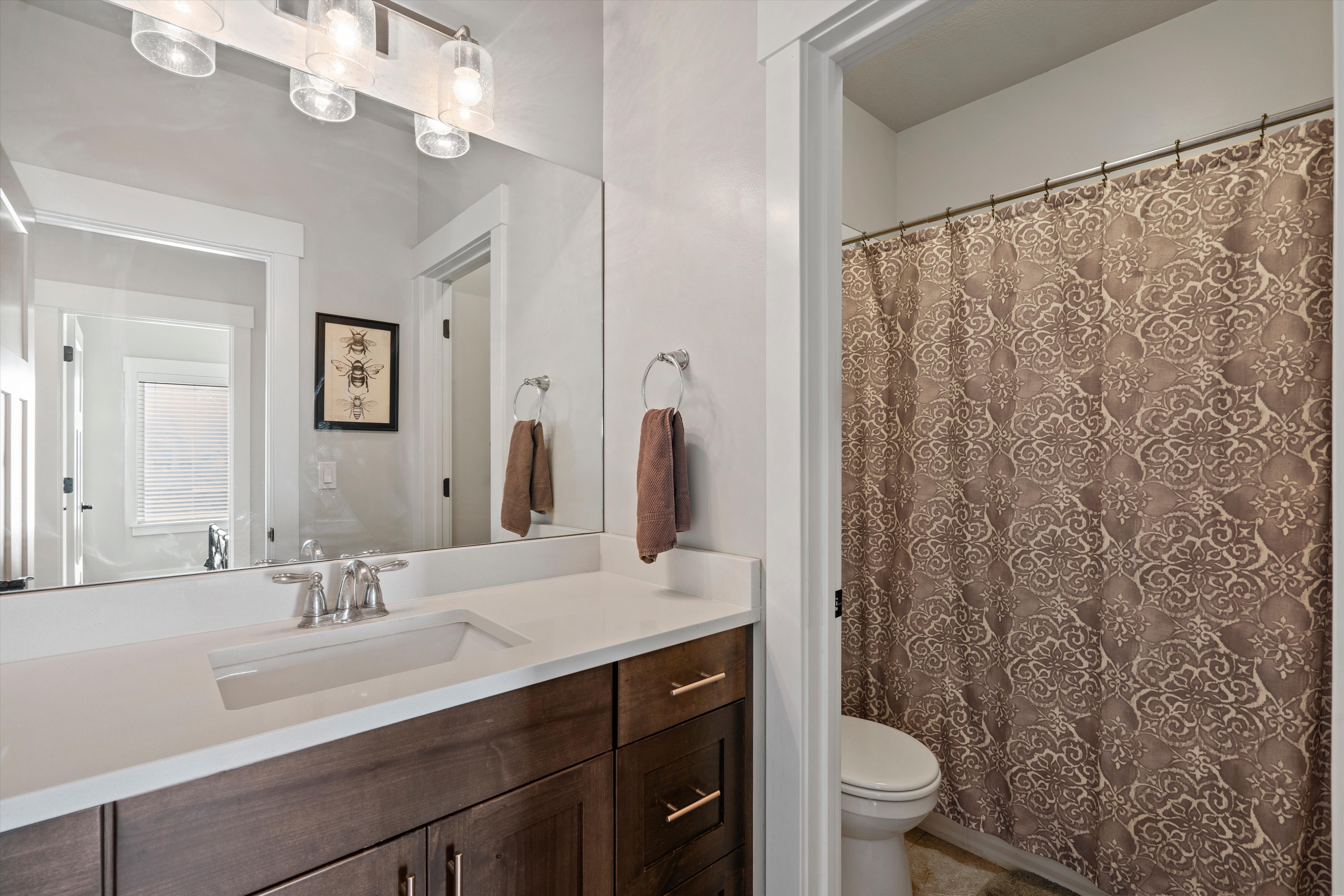 Bathroom featuring a dark wood-finish vanity with a white countertop and an integrated rectangular sink