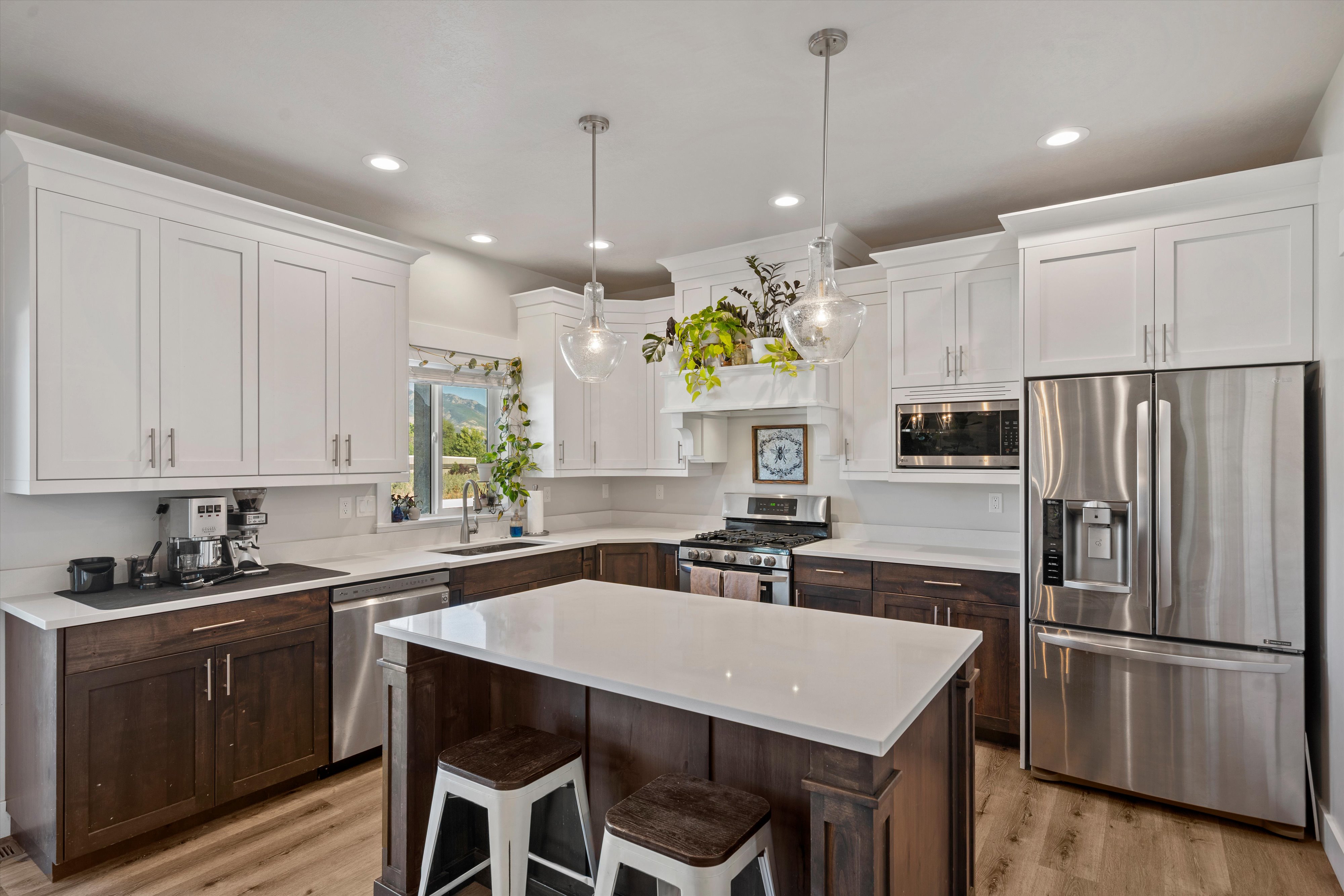Kitchen featuring a central island with countertop seating, white perimeter cabinetry, dark wood-finish lower cabinetry, and stainless-steel appliances