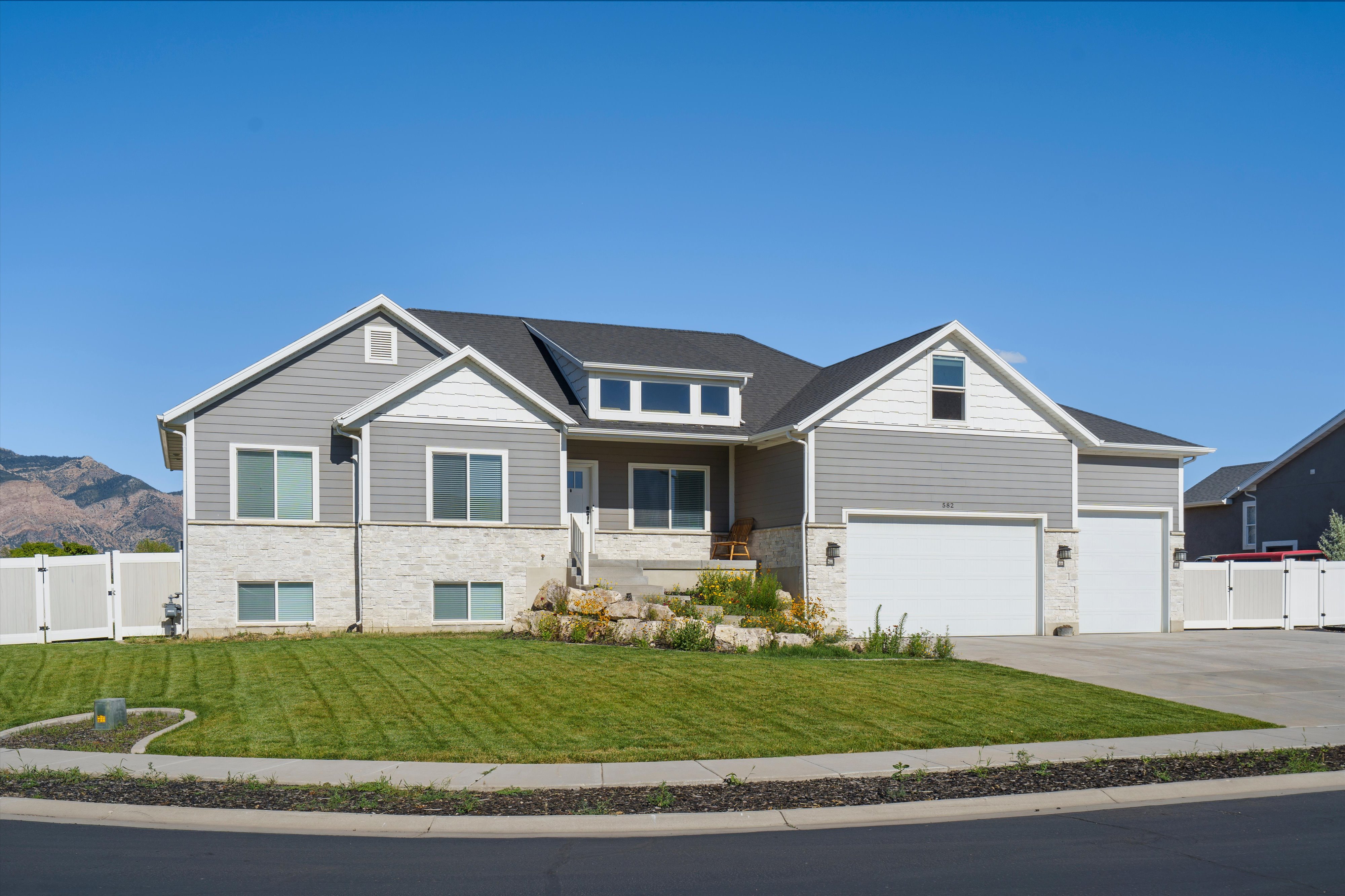 Contemporary two-story residence featuring gray siding and light-colored stone accents