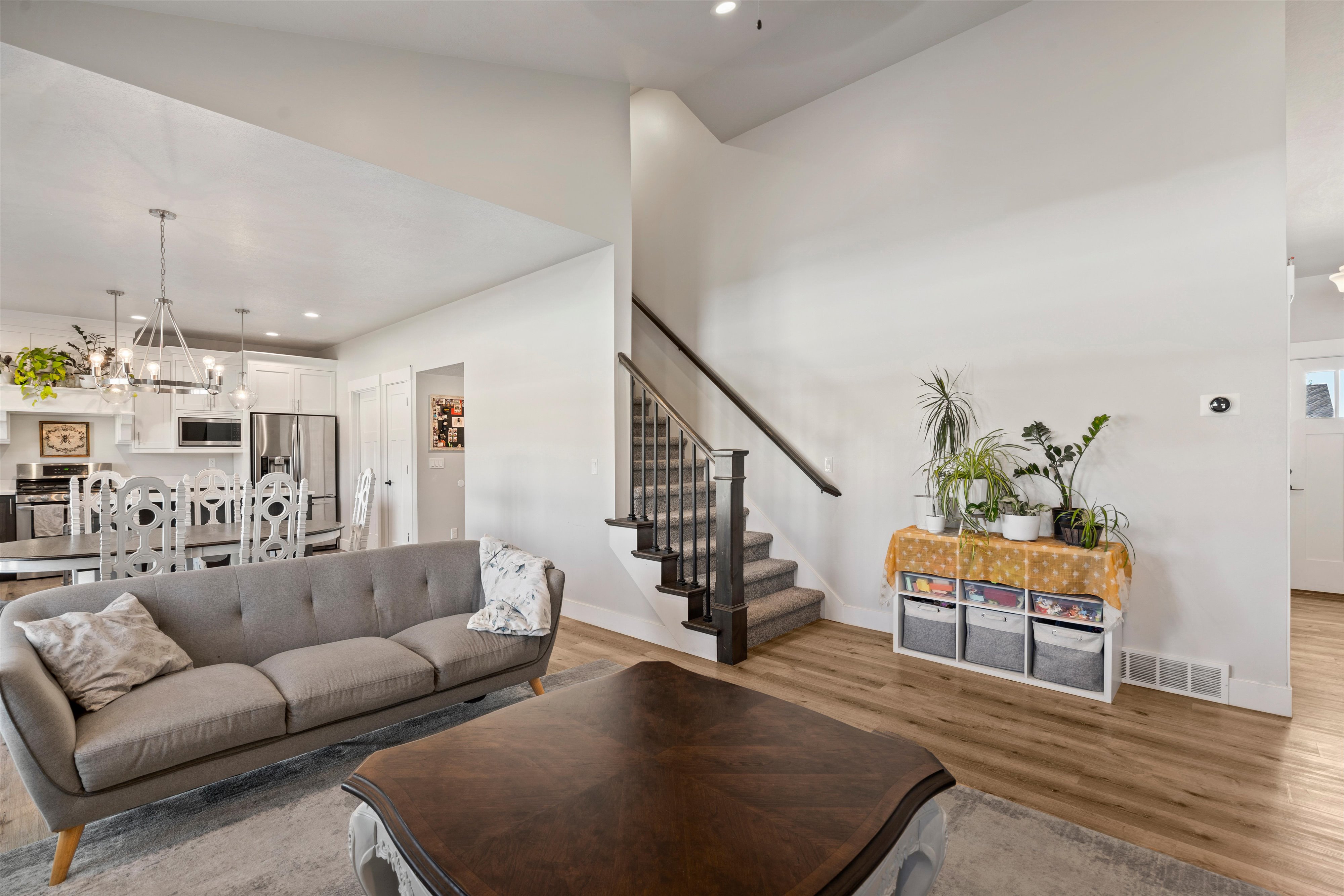 Open-concept living space featuring wood-finish flooring and a staircase with a dark wood newel post and balusters