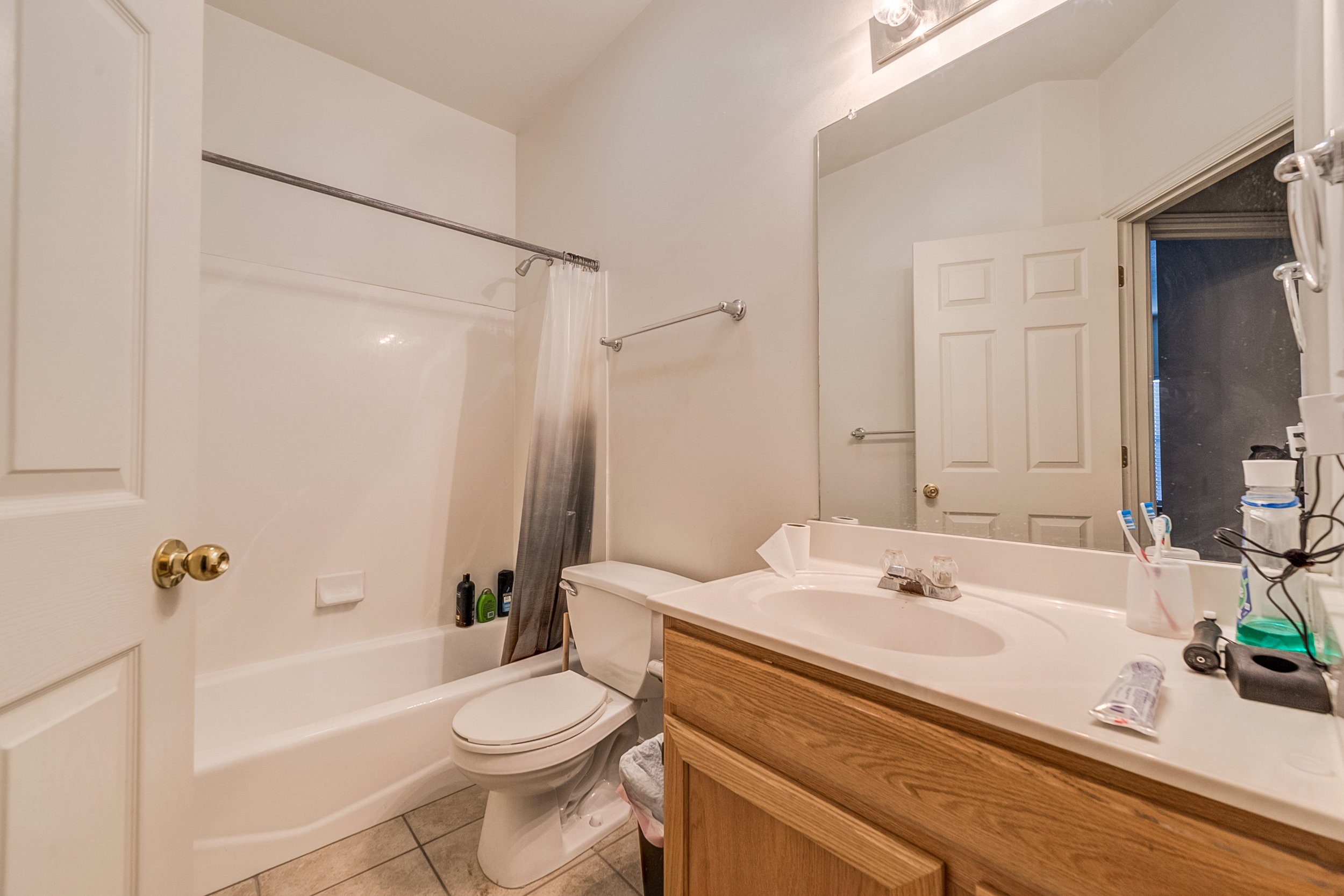 Full bathroom featuring a white tub-shower combination, a white toilet, and a wood-finish vanity with an integrated sink and mirror