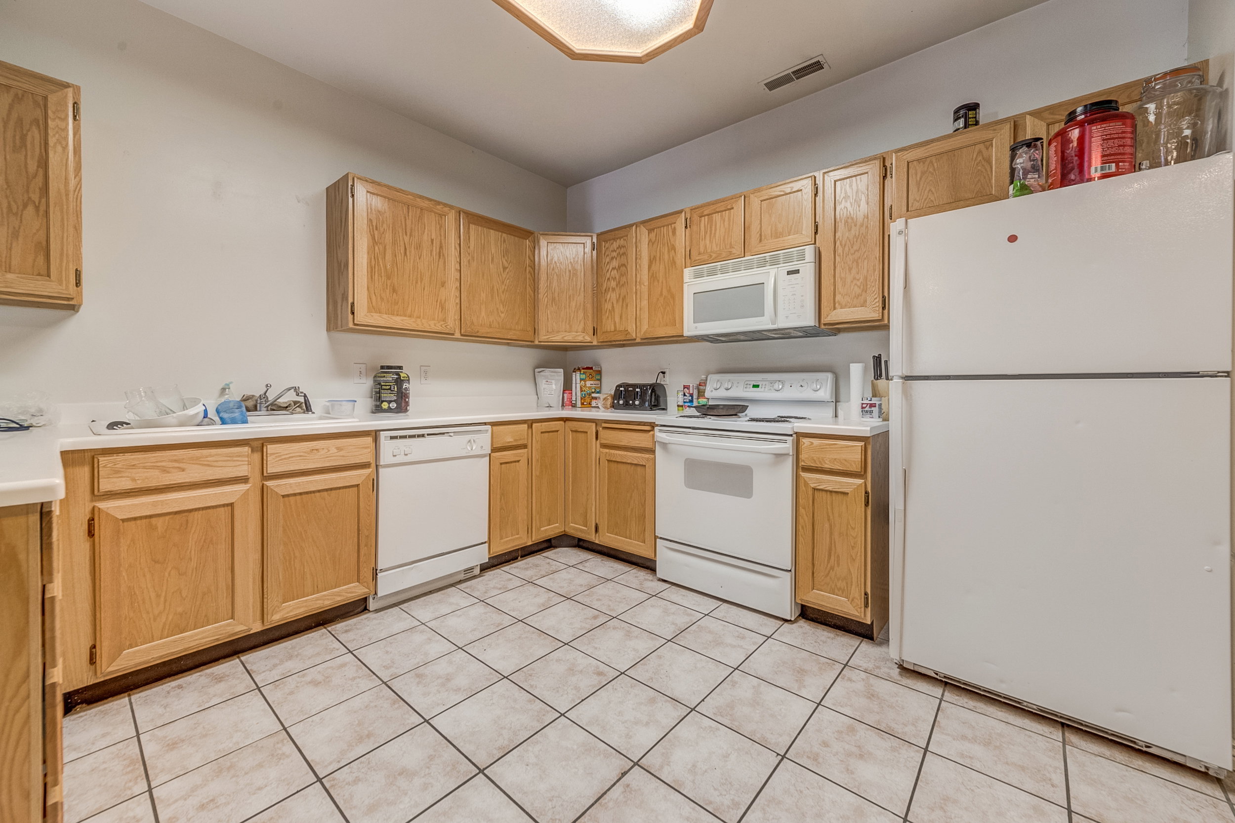 Kitchen featuring wood-finish cabinetry, white countertops, and white appliances