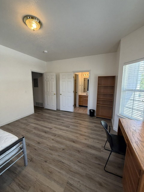 Room featuring wood-finish flooring, white walls, and a ceiling-mounted light fixture