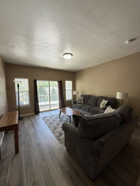 Living area featuring wood-finish flooring, a sliding glass door, and multiple windows