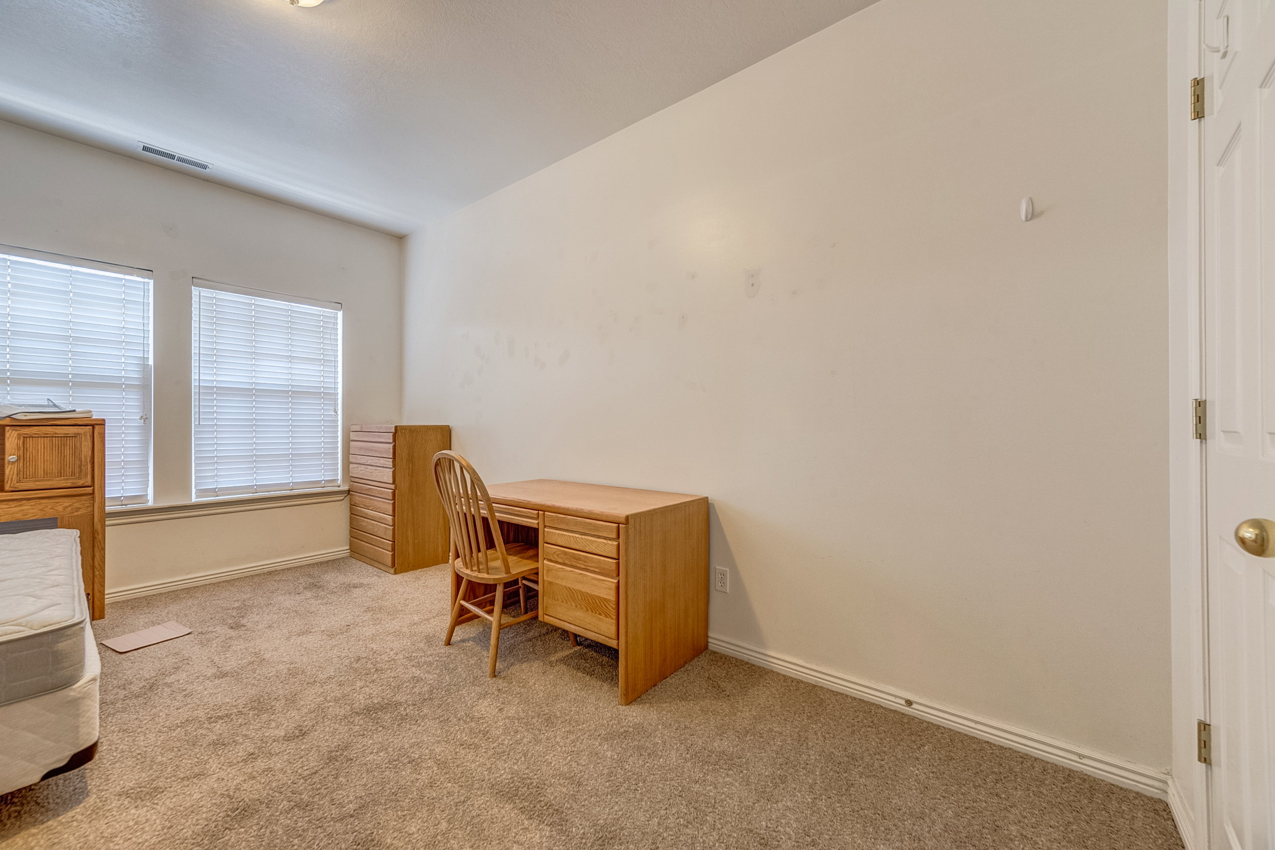 Carpeted room featuring dual windows with blinds, a ceiling light fixture, and white trim