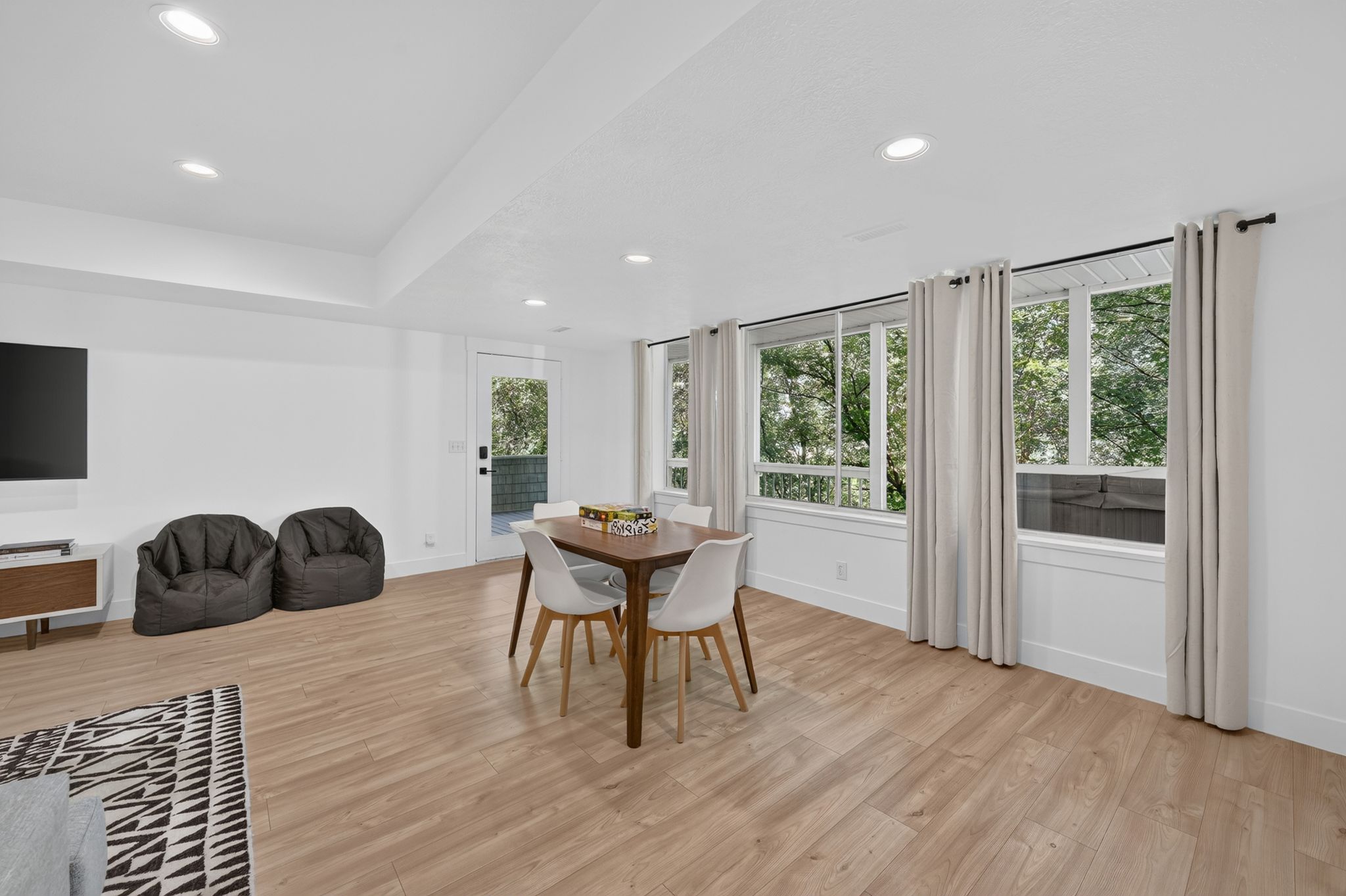 Bright interior space featuring recessed lighting, light wood-finish flooring, multiple windows, a rear exterior door, and white walls