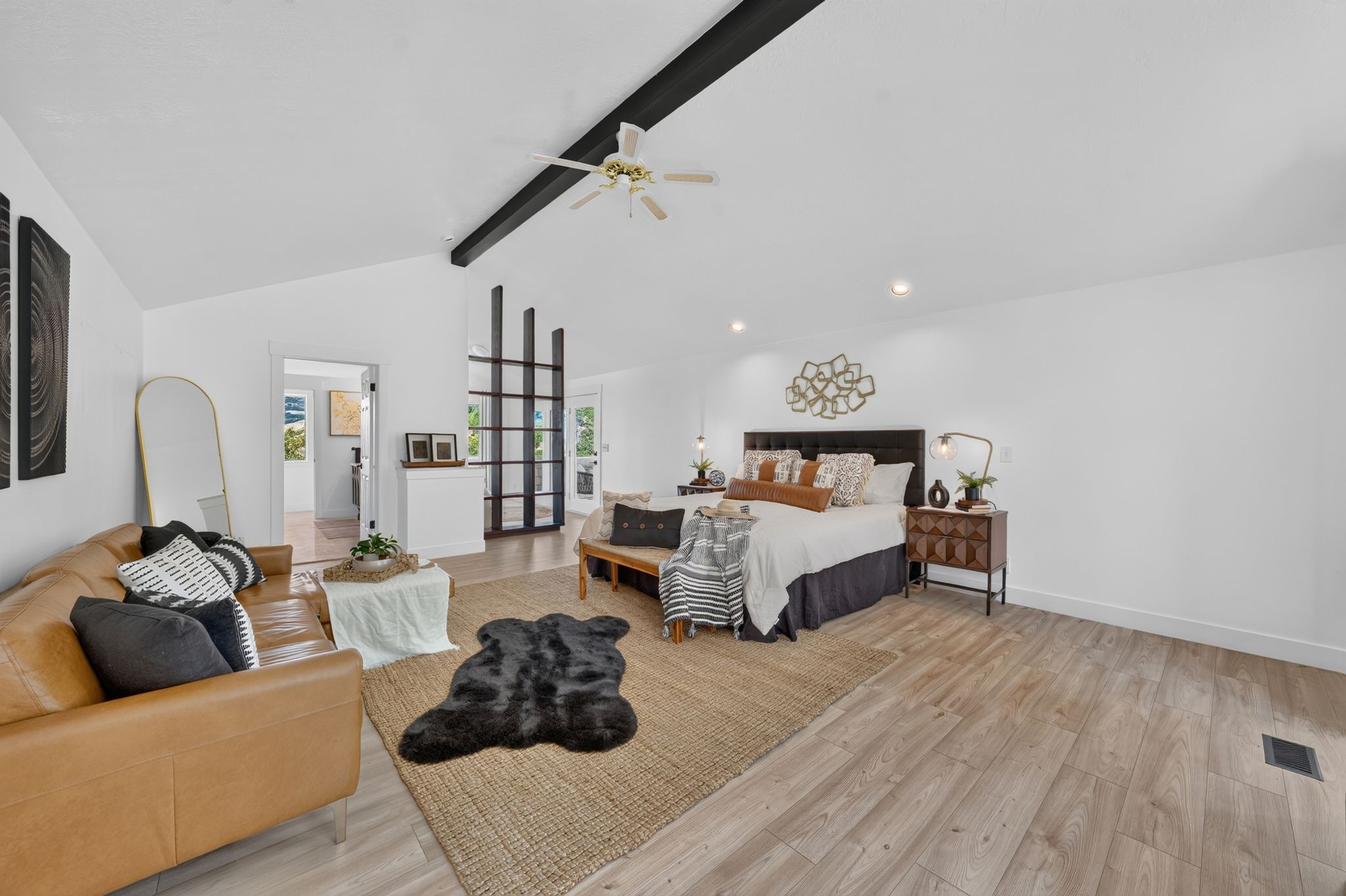 Spacious room featuring vaulted ceilings with exposed dark beams, wood-finish flooring, and recessed lighting