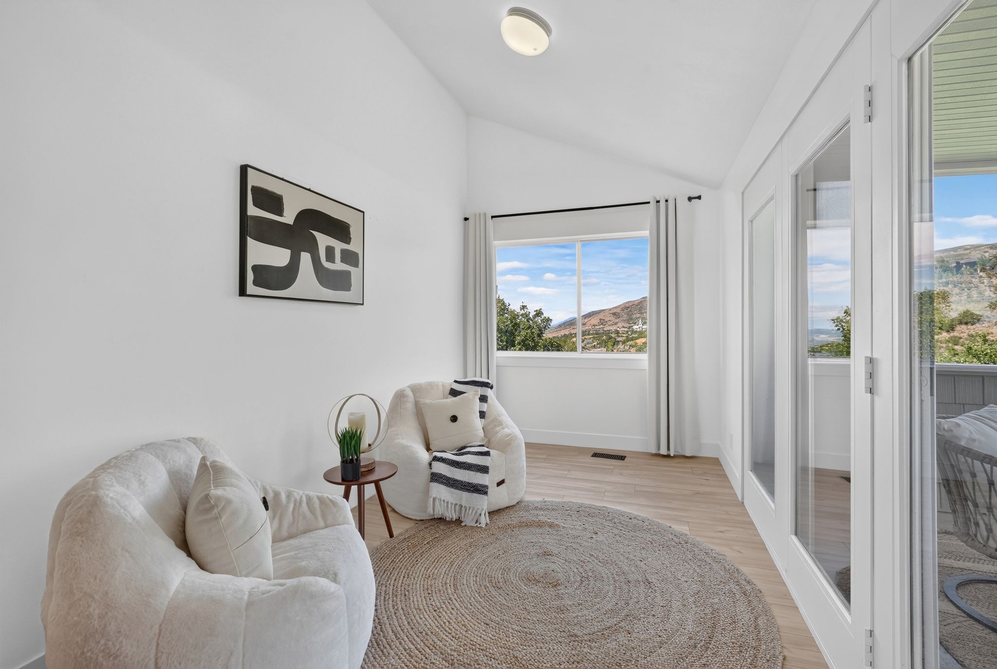 Bright interior space featuring vaulted ceilings, light wood-finish flooring, and a large window offering expansive mountain scenery