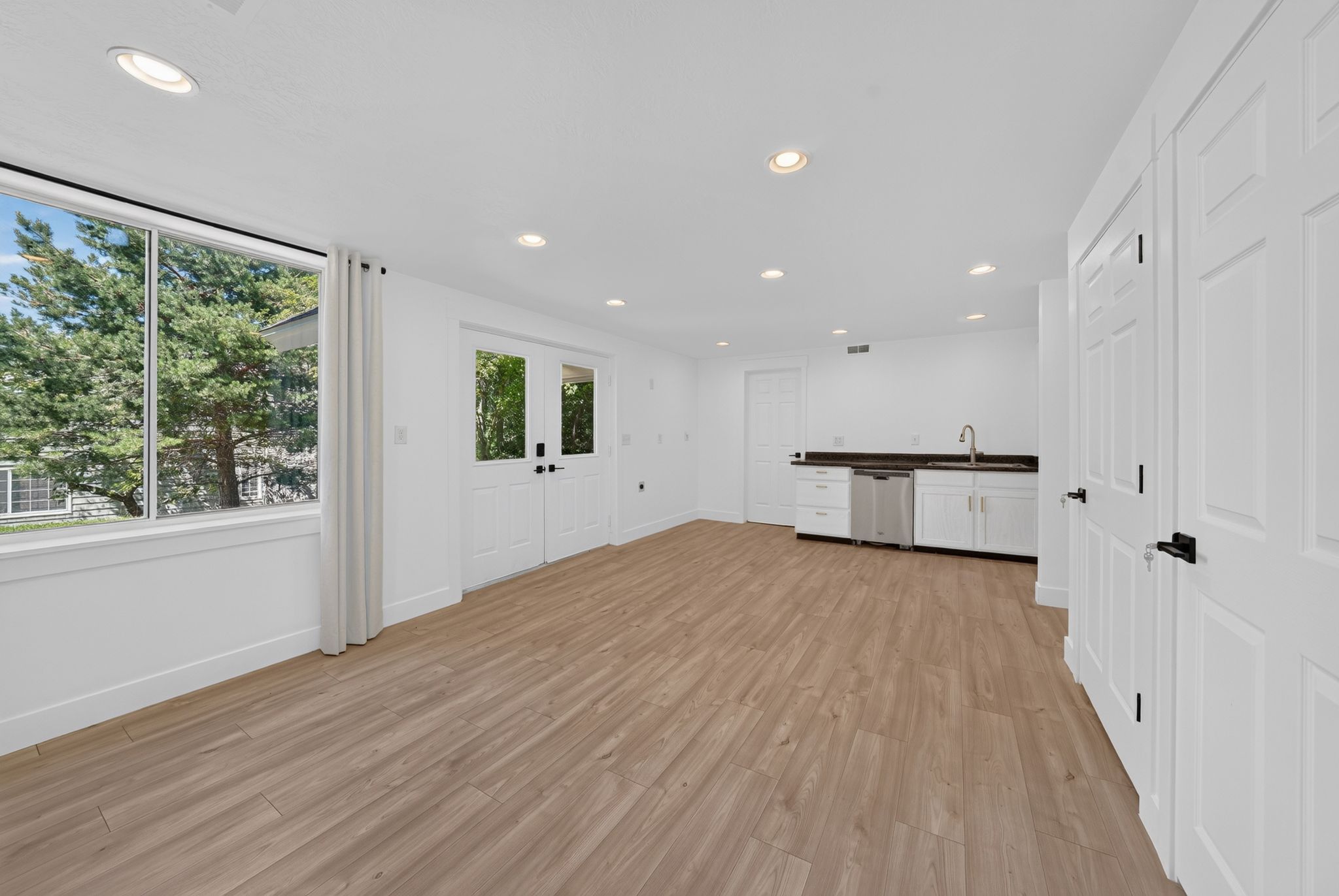 Spacious room with wood-finish flooring, recessed lighting, and a prominent window