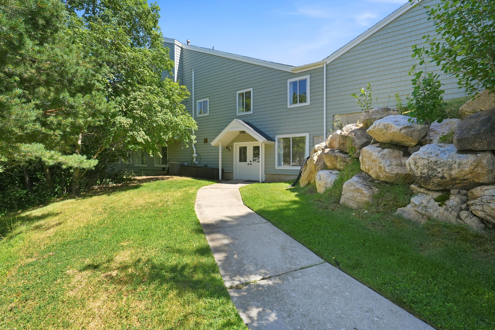 Light green multi-story exterior with white trim windows and a covered entry