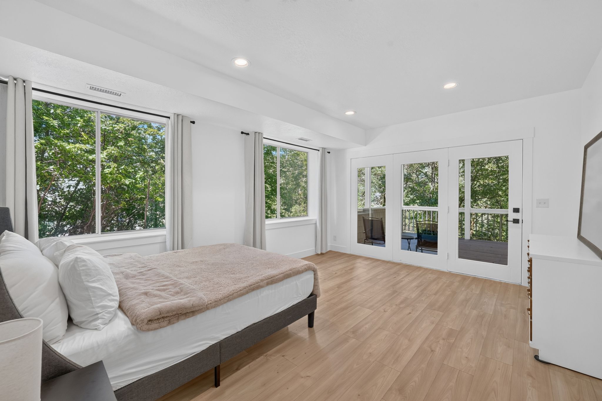 Bright interior with light wood-finish flooring, recessed lighting, and large windows