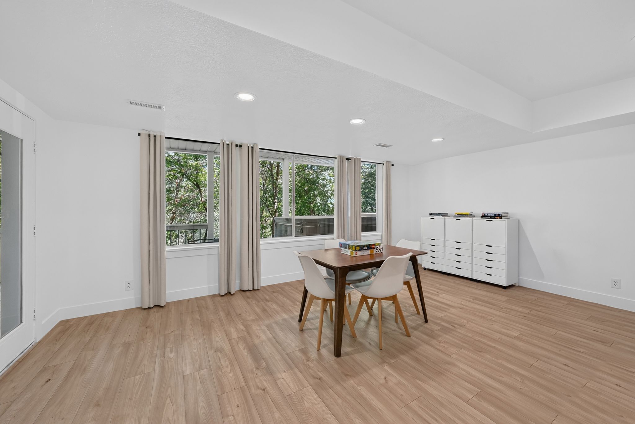 Spacious room featuring wood-finish flooring, white walls, and recessed lighting