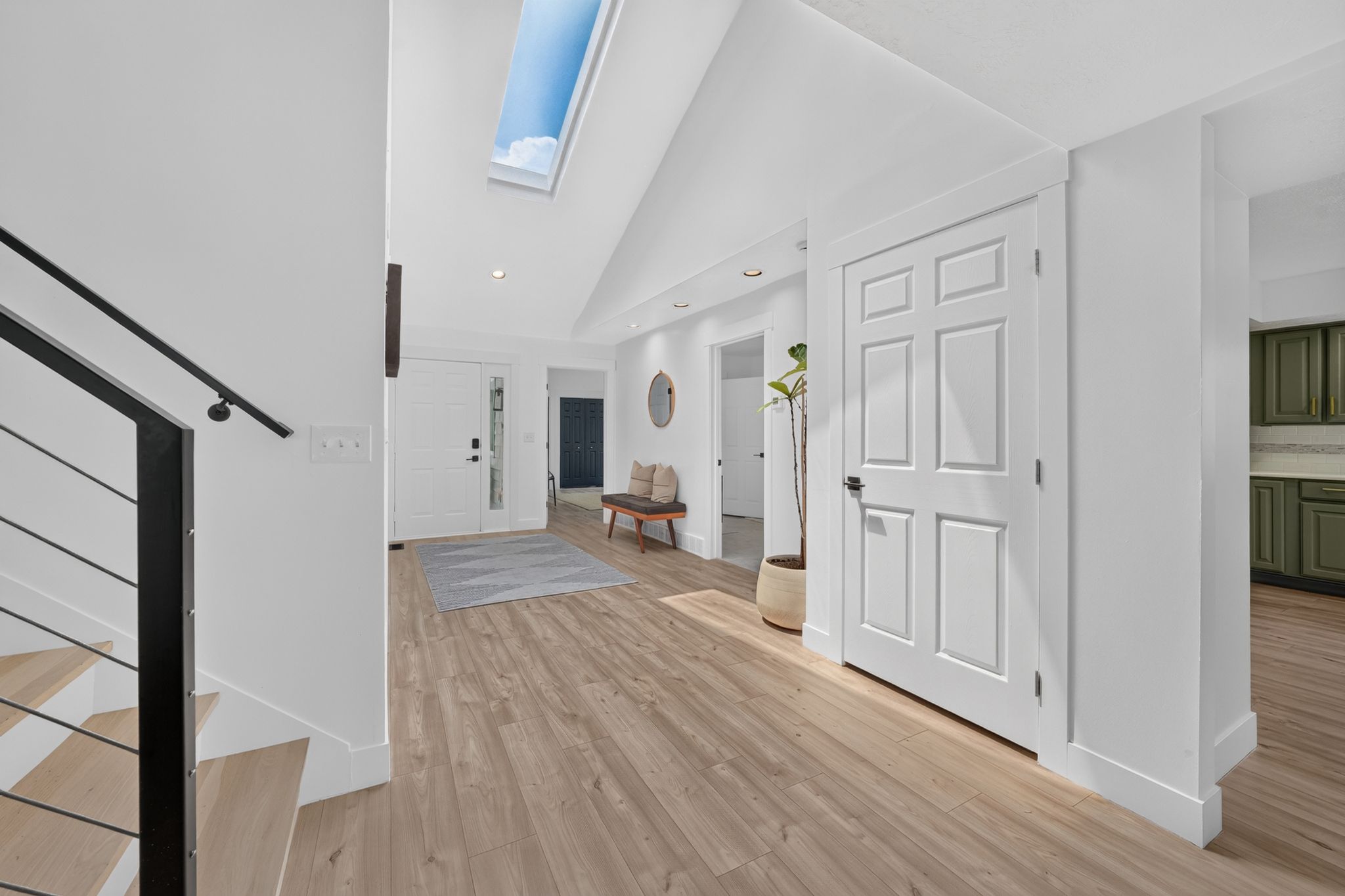 Bright entryway featuring a skylight, wood-finish flooring, white paneled doors, and recessed lighting