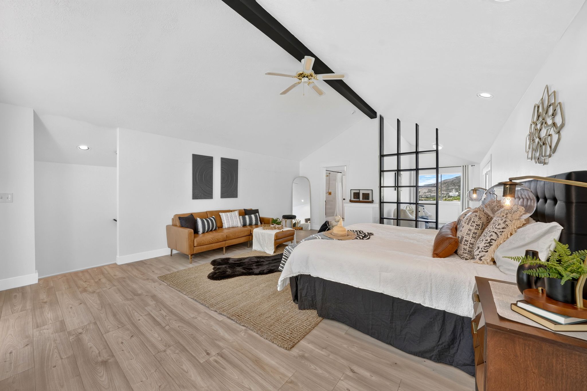 Spacious room featuring vaulted ceilings with exposed beams, wood-finish flooring, a built-in room divider with a grid design, recessed lighting, and a ceiling fan