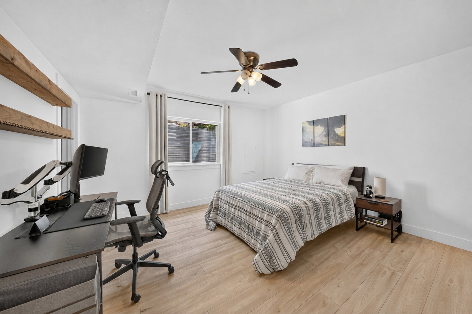 Bedroom featuring light wood-finish flooring, a ceiling fan with integrated lighting, and a recessed window