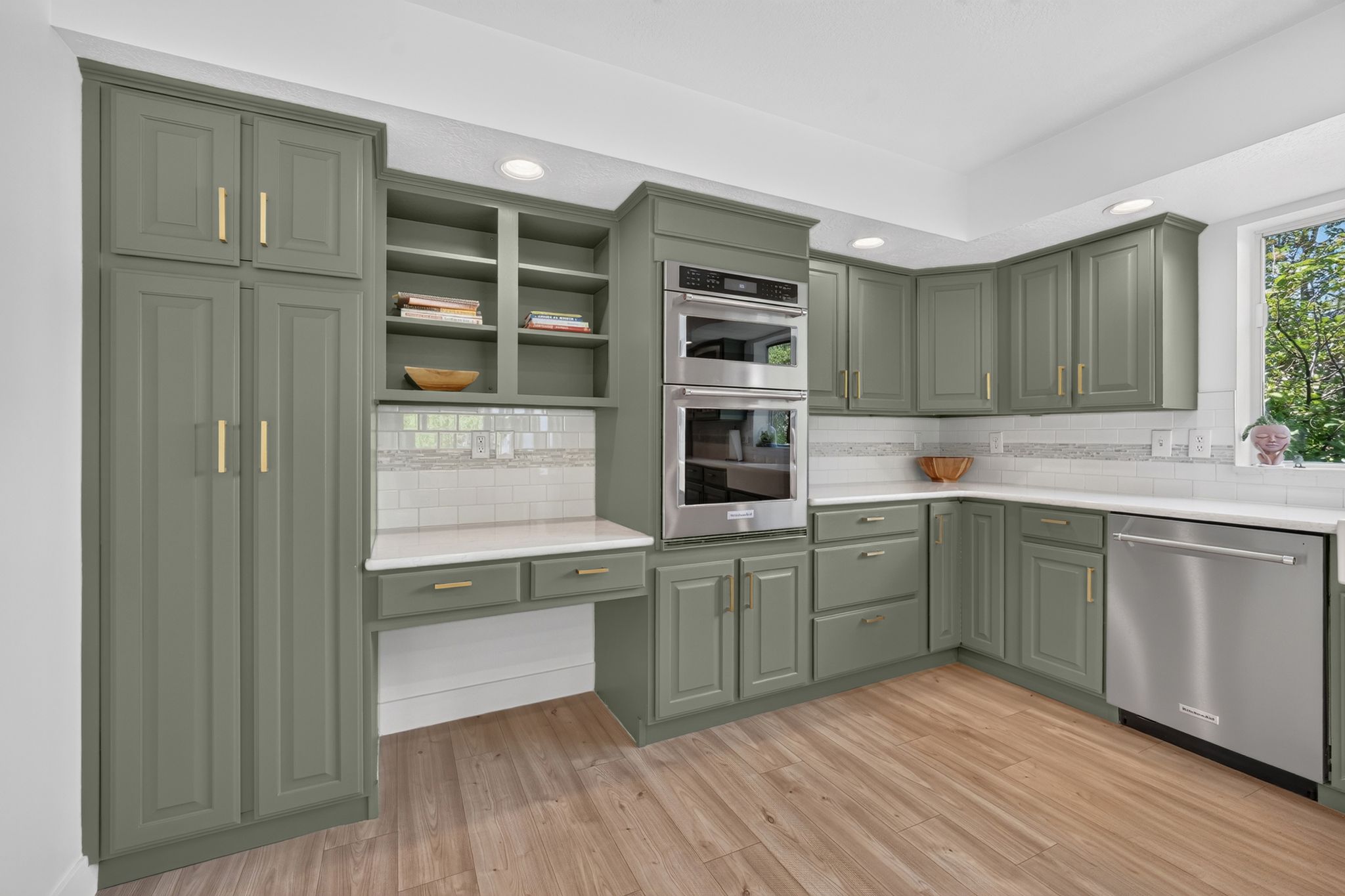 Kitchen featuring wood-finish flooring, recessed lighting, and sage green cabinetry with gold-tone hardware