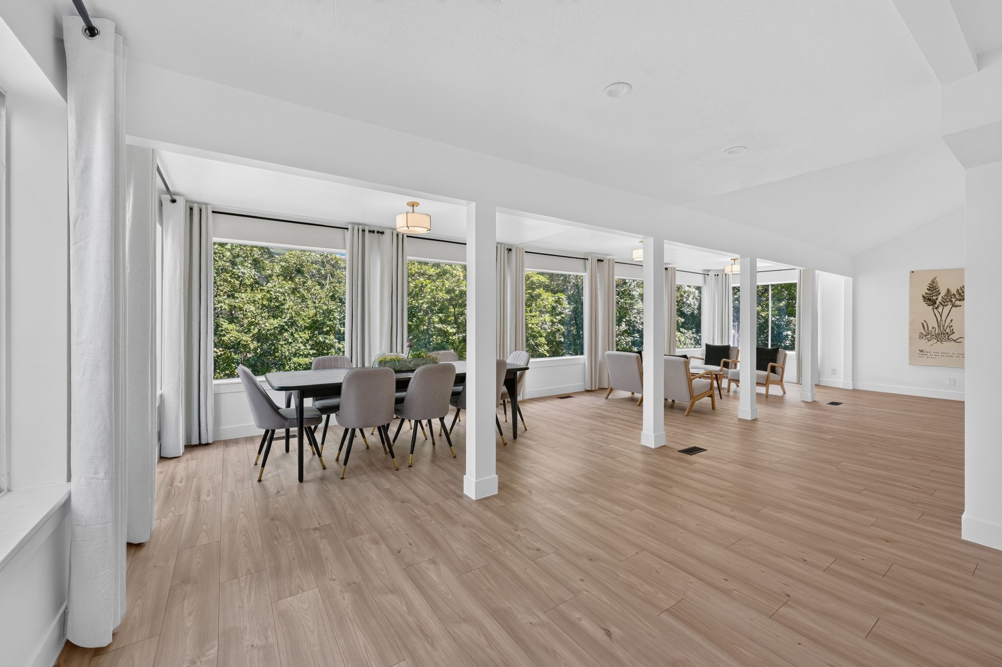 Expansive room featuring wood-finish flooring, abundant natural light from multiple windows, and a vaulted ceiling
