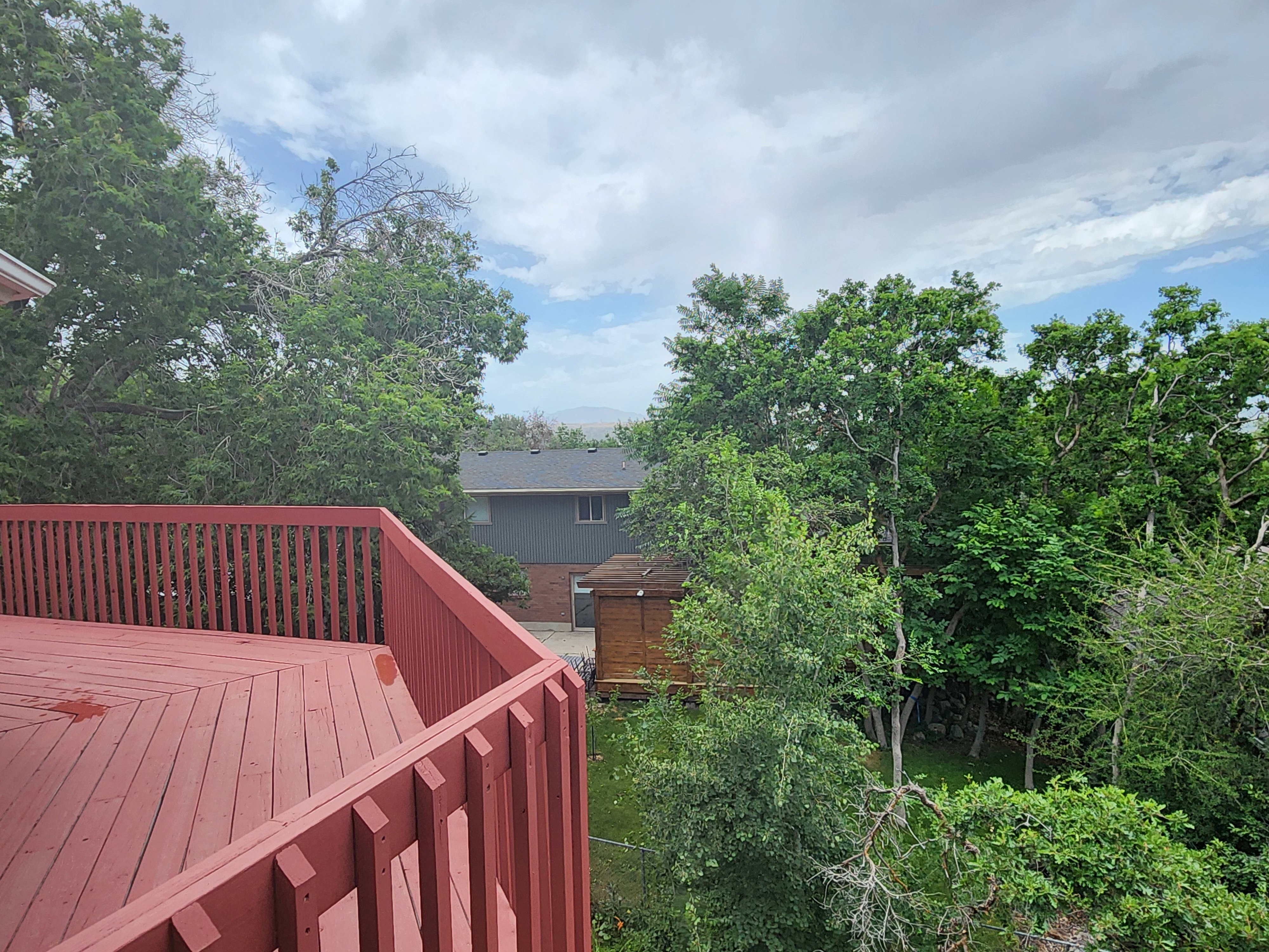 Spacious red-stained wood deck with slatted railings. Some valley view