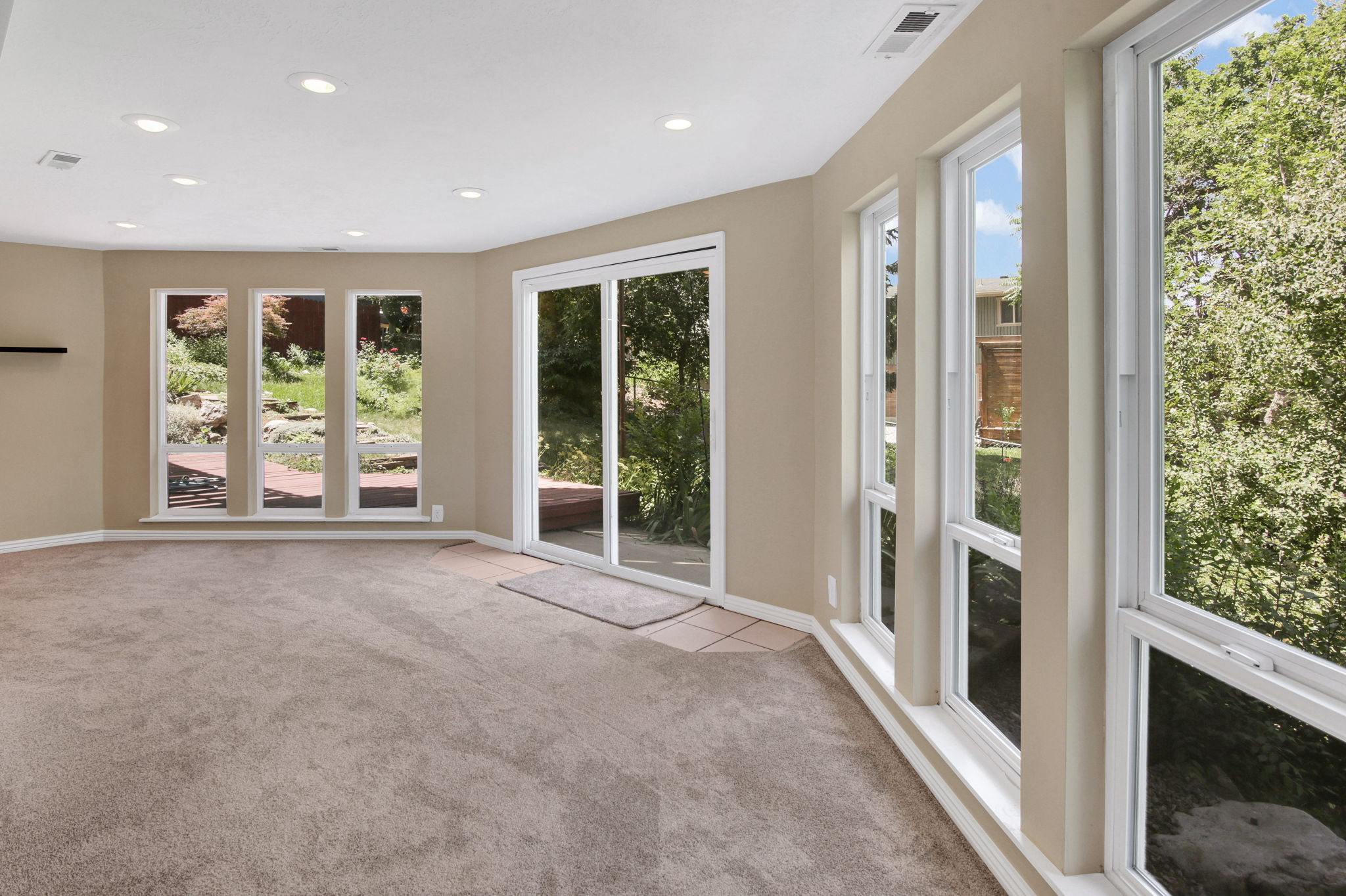 View 2 with lots of view windows and sliding glass door to backyard deck. Recessed lighting illuminates this carpeted room