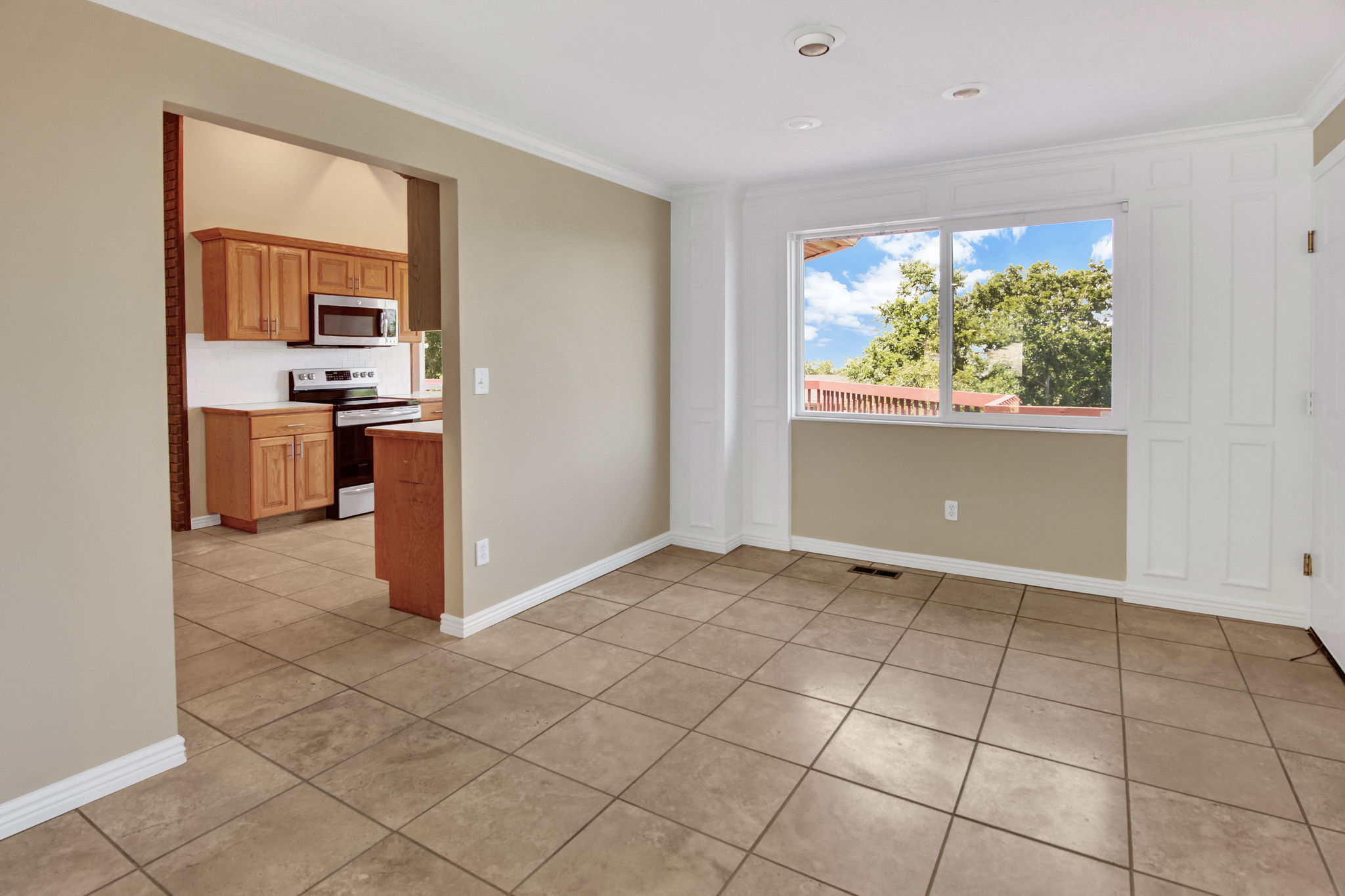 Formal dining with large view window with white paneling. Access garage from the far right of photo. View into kitchen