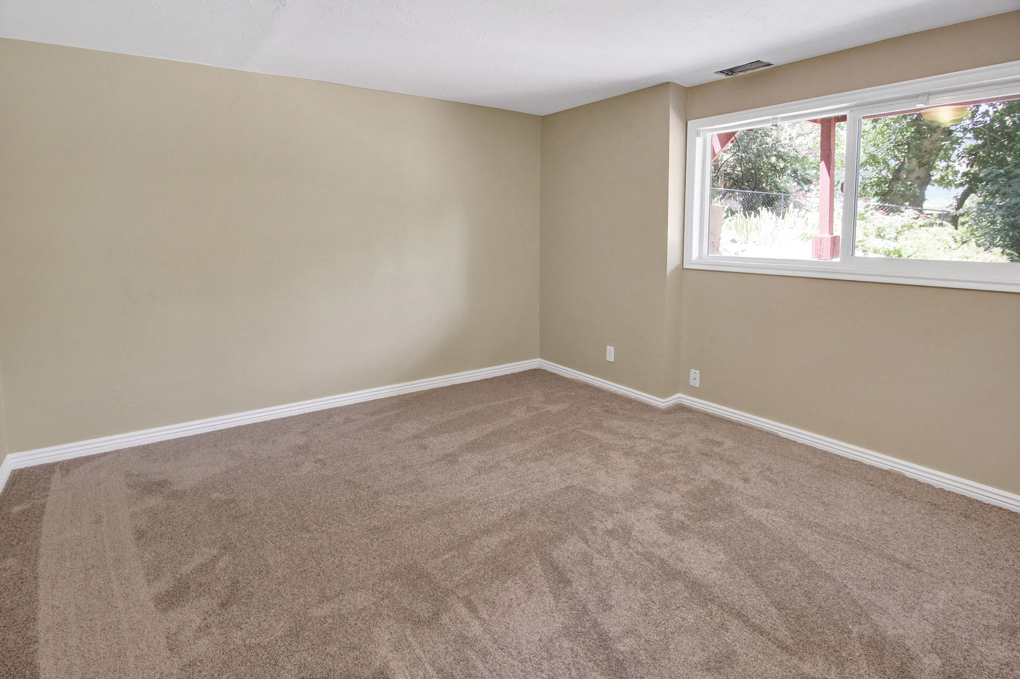Bedroom 5 on 3rd level Spacious room featuring neutral carpeting, light beige walls, white baseboards, and a large white-framed window